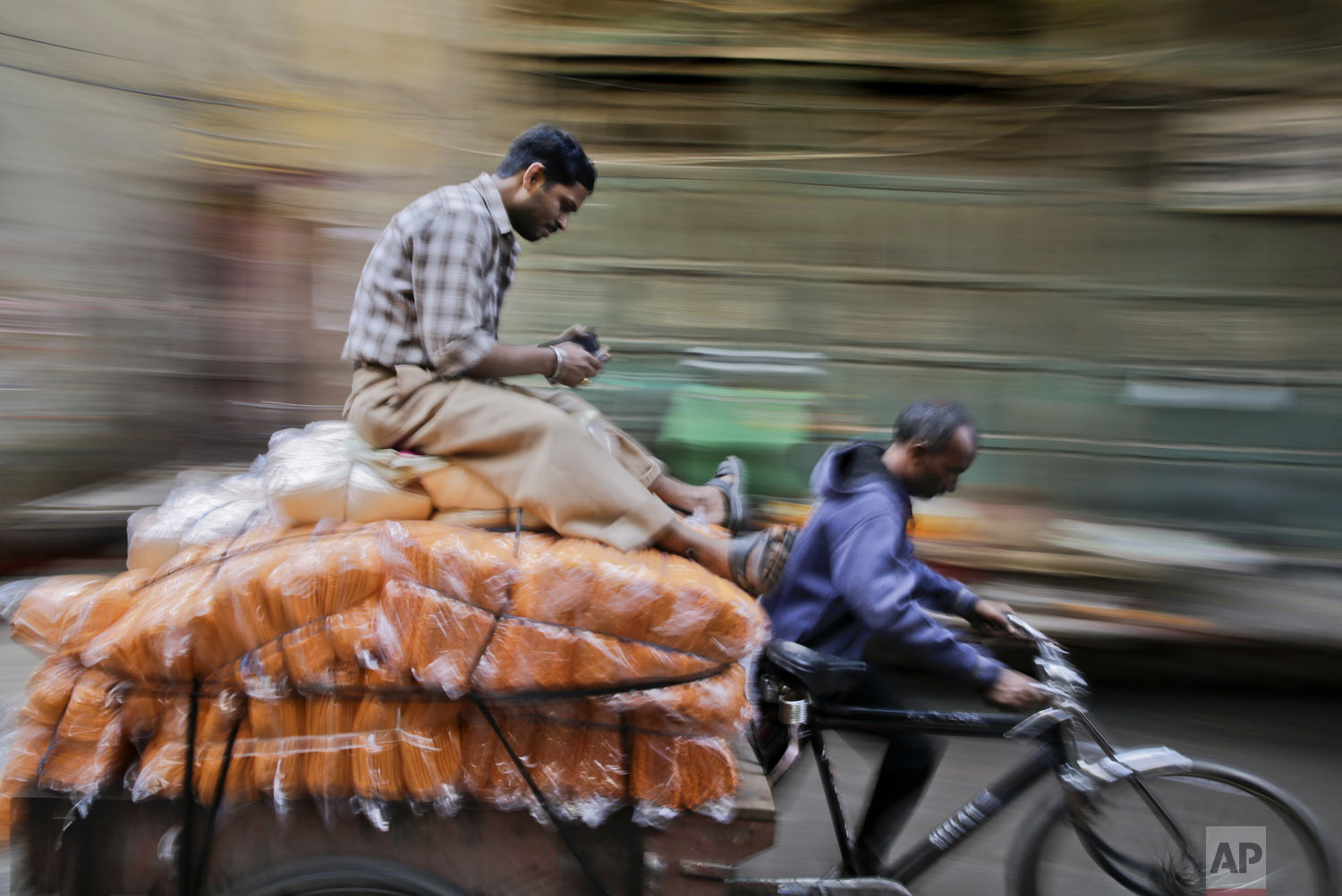  A man sits on stacks of towels transported on a cycle rickshaw cart through a market in the old part of New Delhi, India, Saturday, Dec. 1, 2018. Despite being extremely crowded and dilapidated, the older part of the city still serves as its symboli