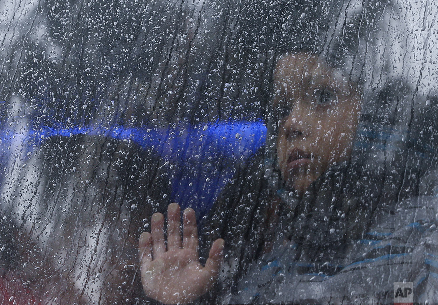  A migrant child looks out of a rainy window of a bus carrying Central Americans from the Barretal migrant shelter to an ongoing job fair where migrants can get help with work permits and local jobs in Tijuana, Mexico, Thursday, Dec. 6, 2018. Many of