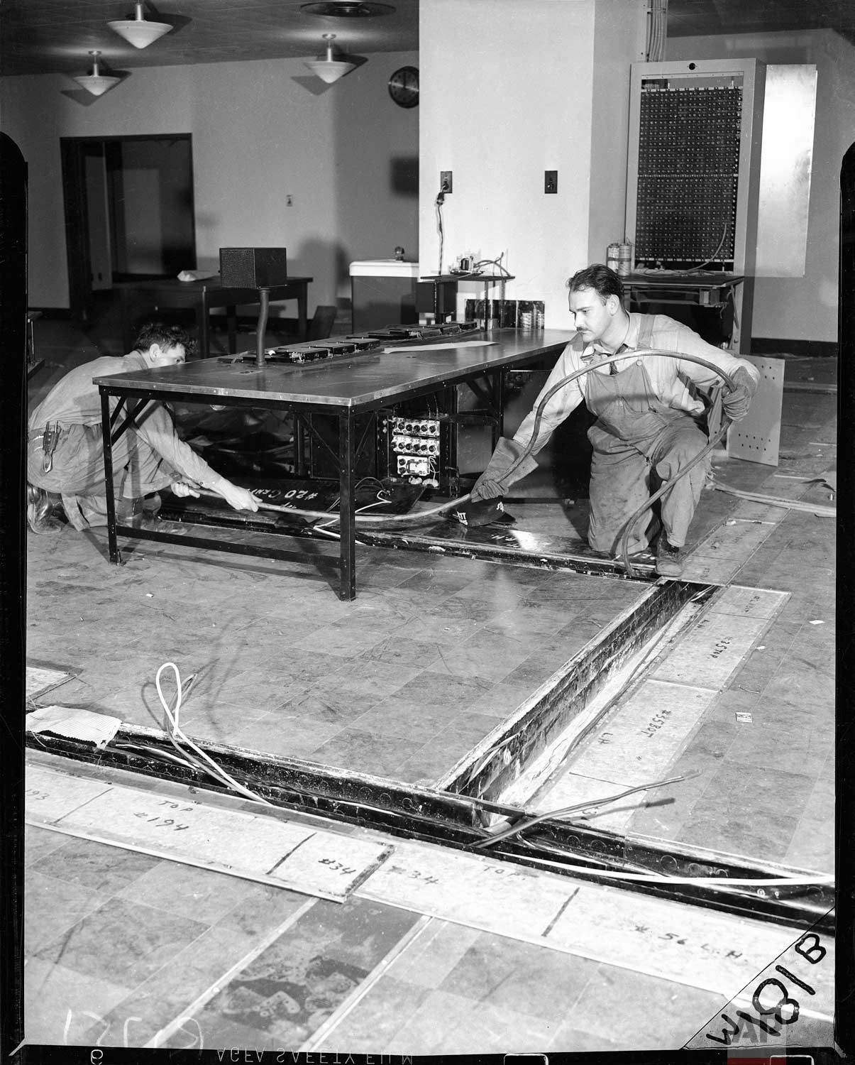  Workers lay cable in floor channels in the market department at Associated Press in the new AP building at Rockefeller Center, New York, in 1938. The market department switchboard and main market operating table are shown.(AP Photo/Corporate Archive