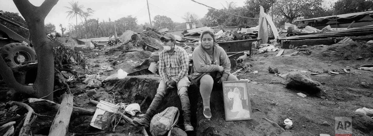 Marlene Vazquez, right, rests next to her cousin Silas Vazquez, as she holds a portrait of their cousins, killed by the Volcan de Fuego, or Volcano of Fire eruption, in San Miguel Los Lotes, Guatemala on June 13, 2018. (AP Photo/Rodrigo Abd)