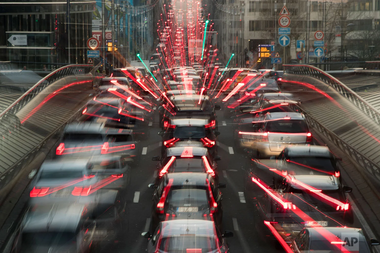 In this slow-shutter zoom effect photo taken on Wednesday, Dec. 12, 2018, commuters are backed up in traffic during the morning rush hour, in Brussels, a city that regularly experiences pollution alert warnings. (AP Photo/Francisco Seco)