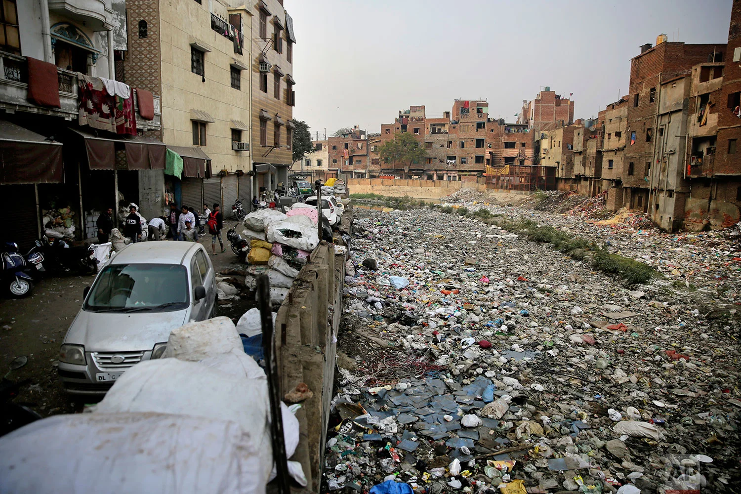 In this Saturday, Dec. 8, 2018 photo, piles of electronic waste is placed next to a drain chocked with plastic and garbage in New Delhi, India. (AP Photo/Altaf Qadri)
