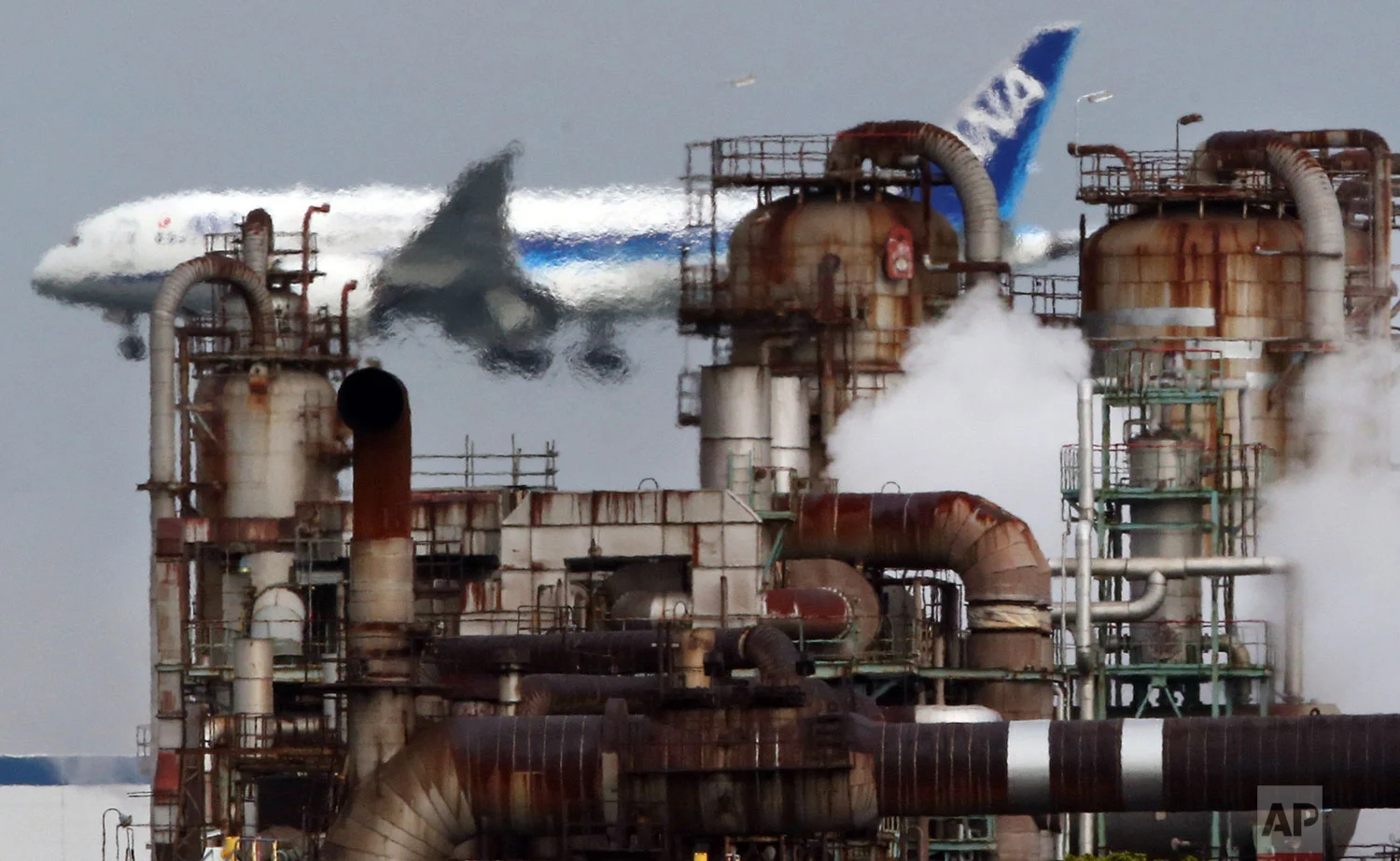 In this Thursday, Dec. 13, 2018 photo, a passenger plane prepares for landing near an oil refinery in Kawasaki, southwest of Tokyo. (AP Photo/Koji Sasahara)