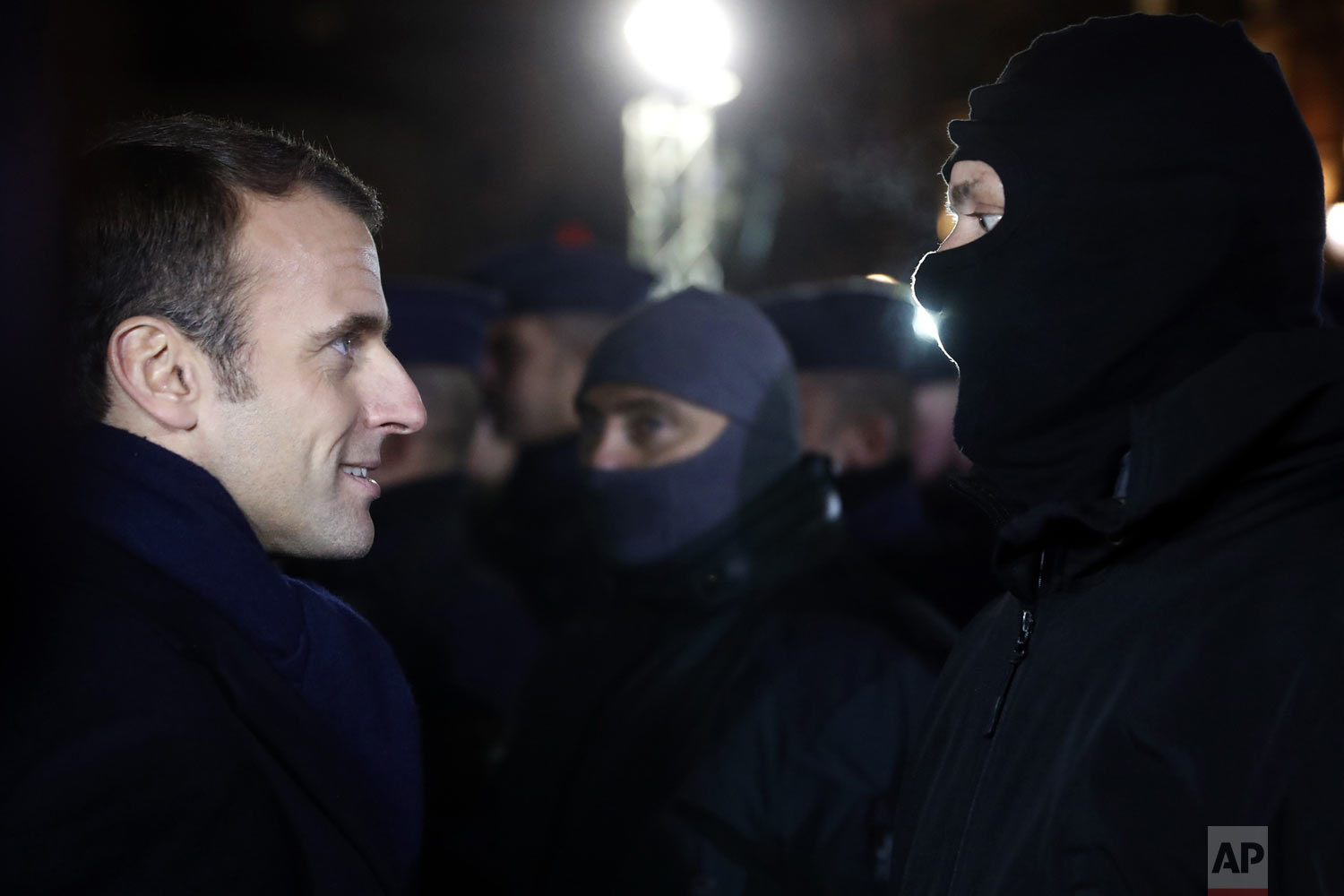  French President Emmanuel Macron meets police officers wearing hoods near the Christmas market in Strasbourg, eastern France, Friday, Dec.14, 2018. A fourth person died Friday from wounds suffered in an attack on the Christmas market in Strasbourg, 
