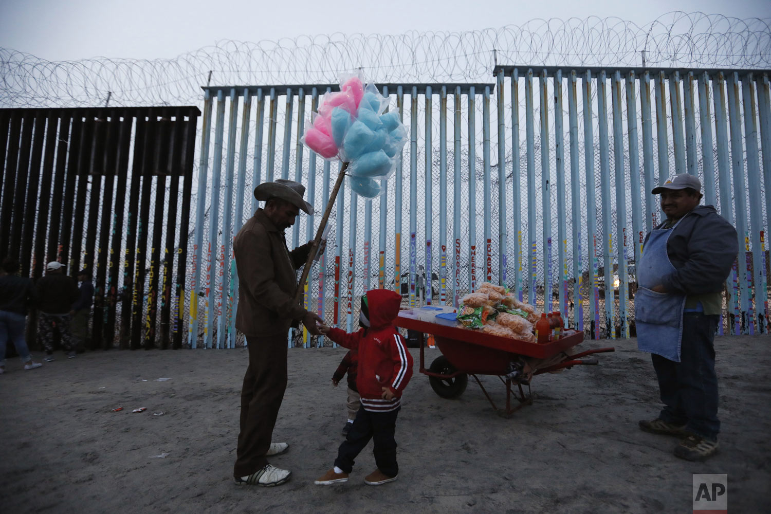  A Honduran migrant boy tries to buy cotton candy from a vendor, but doesn't have enough money, as migrants visit the U.S. border wall to look for opportunities to cross, at the beach in Tijuana, Mexico, on Sunday, Dec. 9, 2018. Discouraged by the lo