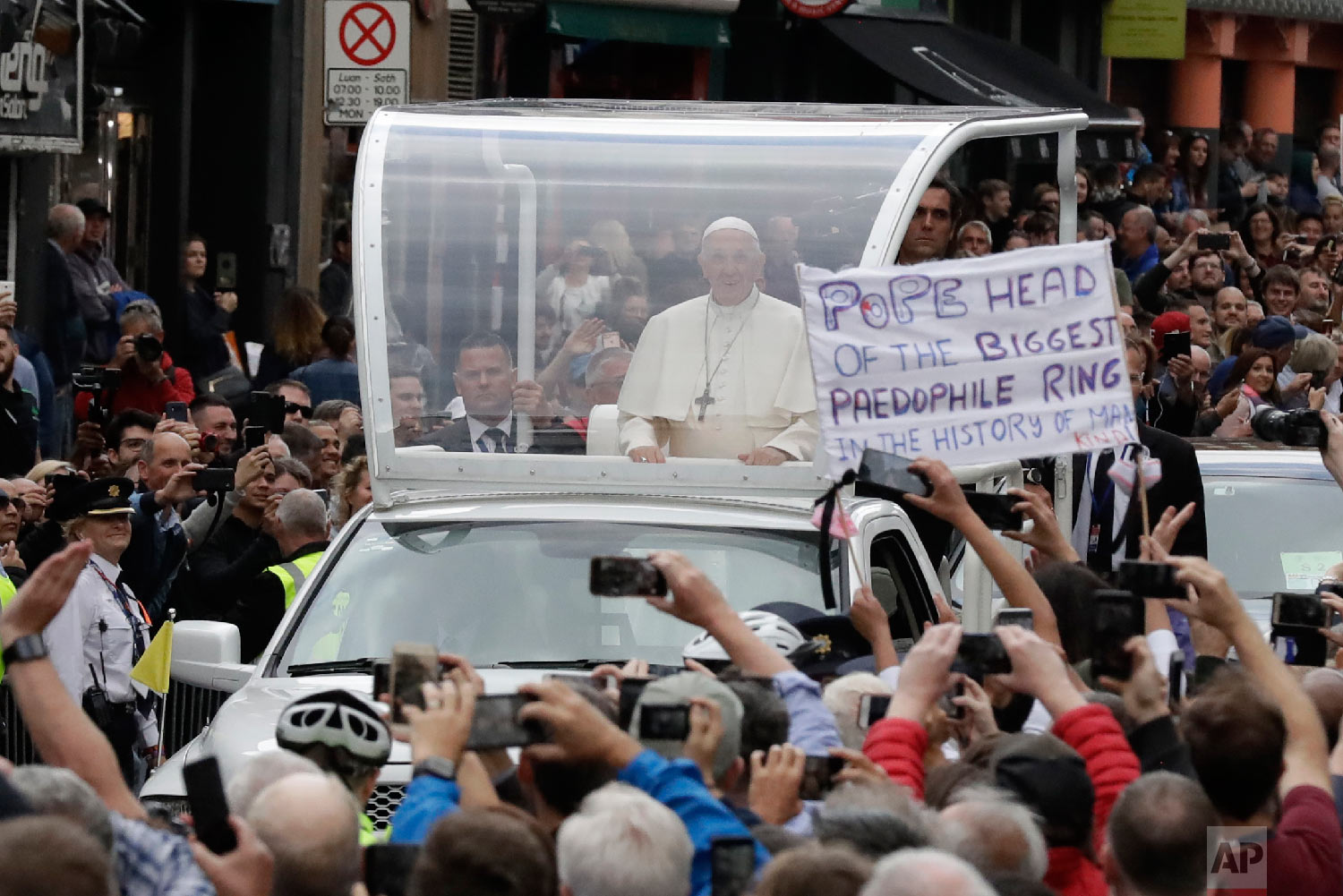  Pope Francis passes by a banner of a protester as he leaves after visiting St Mary's Pro-Cathedral, in Dublin, Ireland. Pope Francis is on a two-day visit to Ireland on Aug. 25, 2018. (AP Photo/Matt Dunham) 