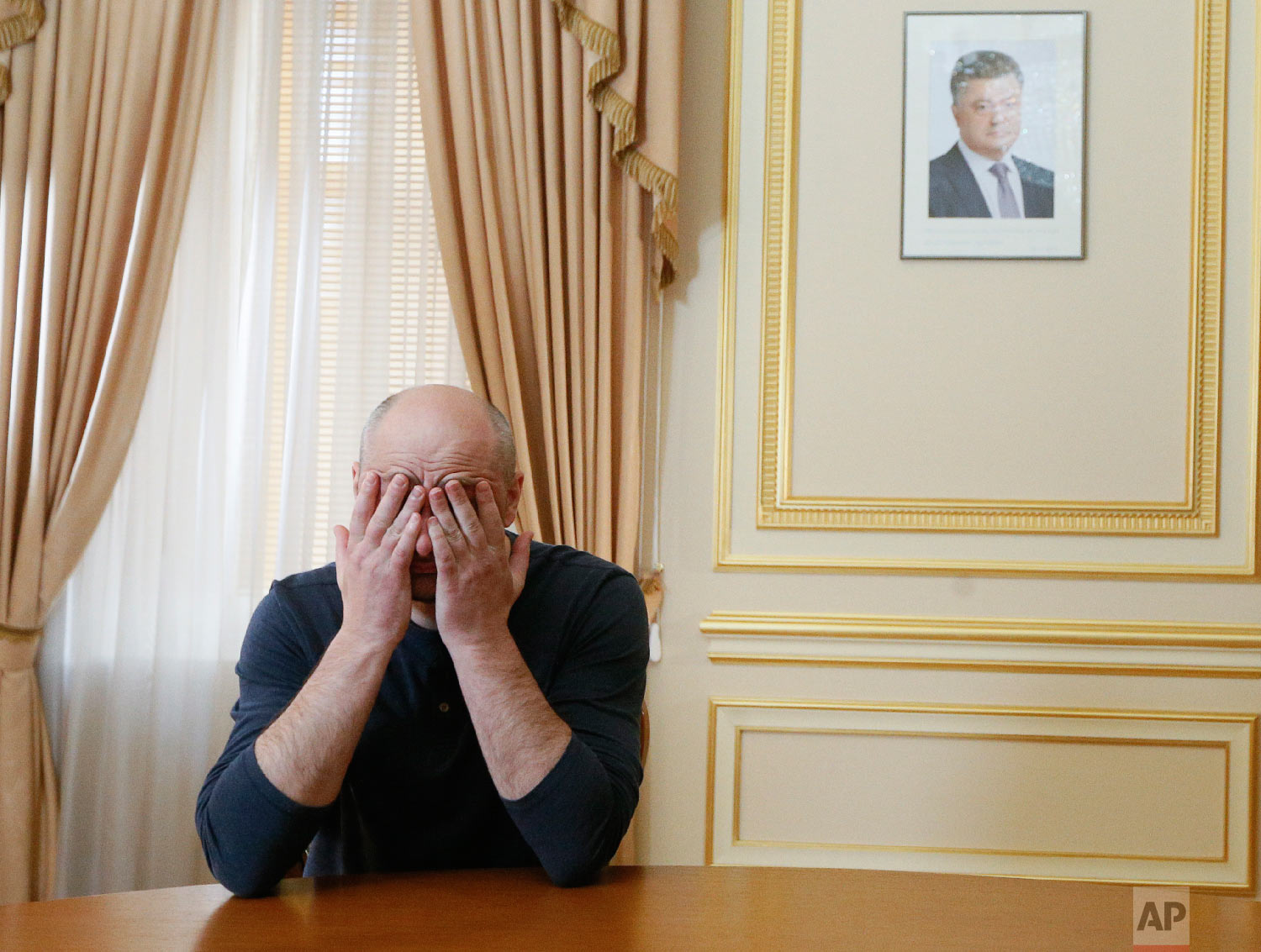  Russian journalist Arkady Babchenko holds his face during an interview with foreign media, with the portrait of Ukrainian President Petro Poroshenko, right in the background, in Kiev, Ukraine on May 31, 2018. (Valentyn Ogirenko/Pool Photo via AP) 