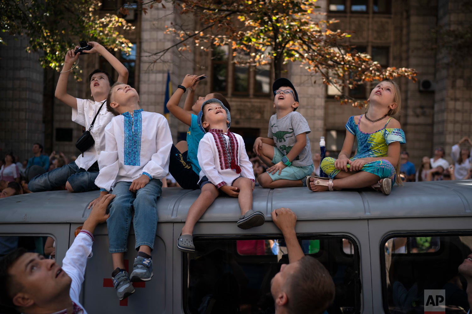  Children look up as military aircrafts fly above the city center during a military parade to celebrate Independence Day in Kiev, Ukraine on Aug. 24, 2018. (AP Photo/Felipe Dana) 