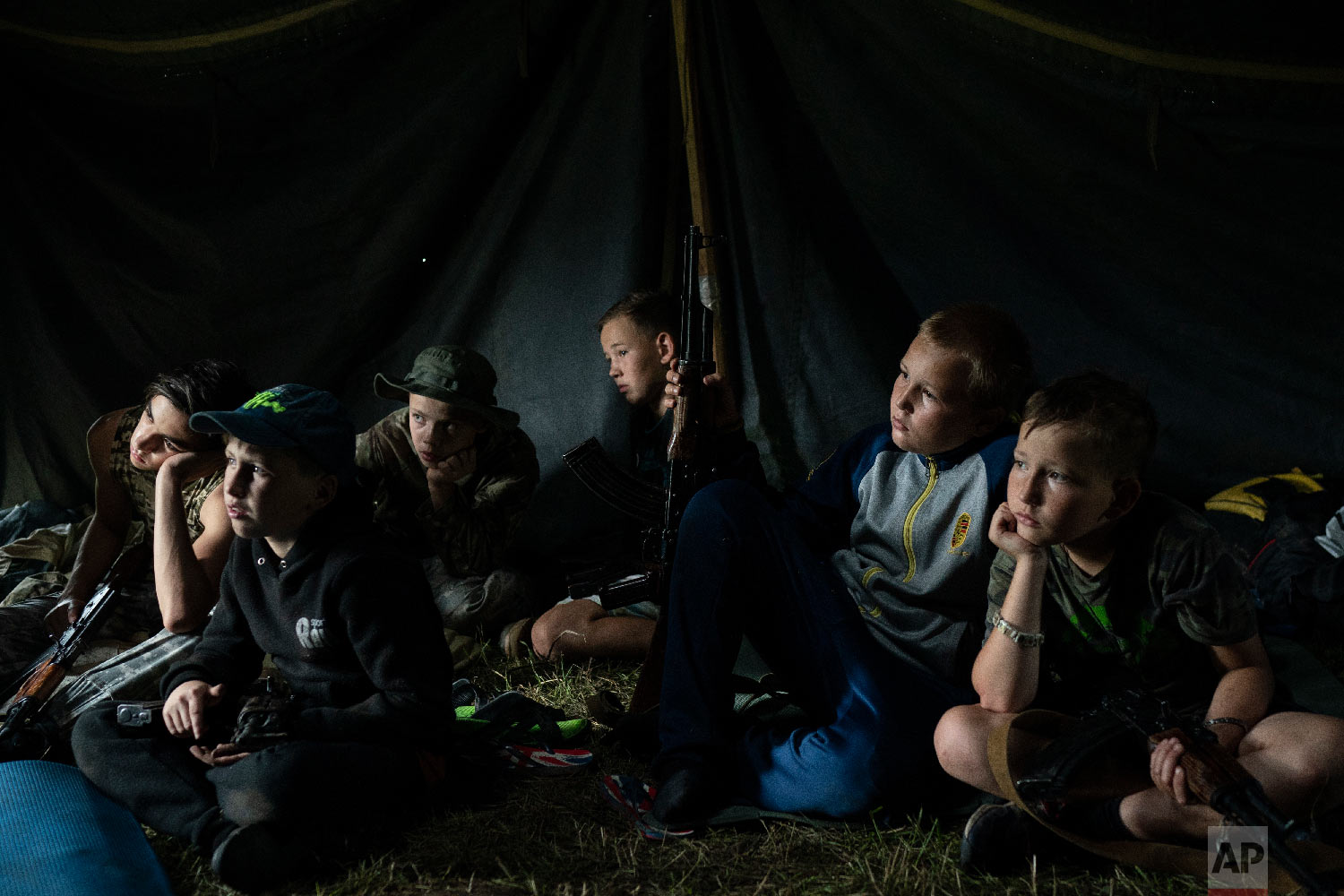  Young participants of the "Temper of will" summer camp, organized by the nationalist Svoboda party, sit inside a tent with their AK-47 riffles as they receive instructions during a tactical exercise in a village near Ternopil, Ukraine on July 28, 20