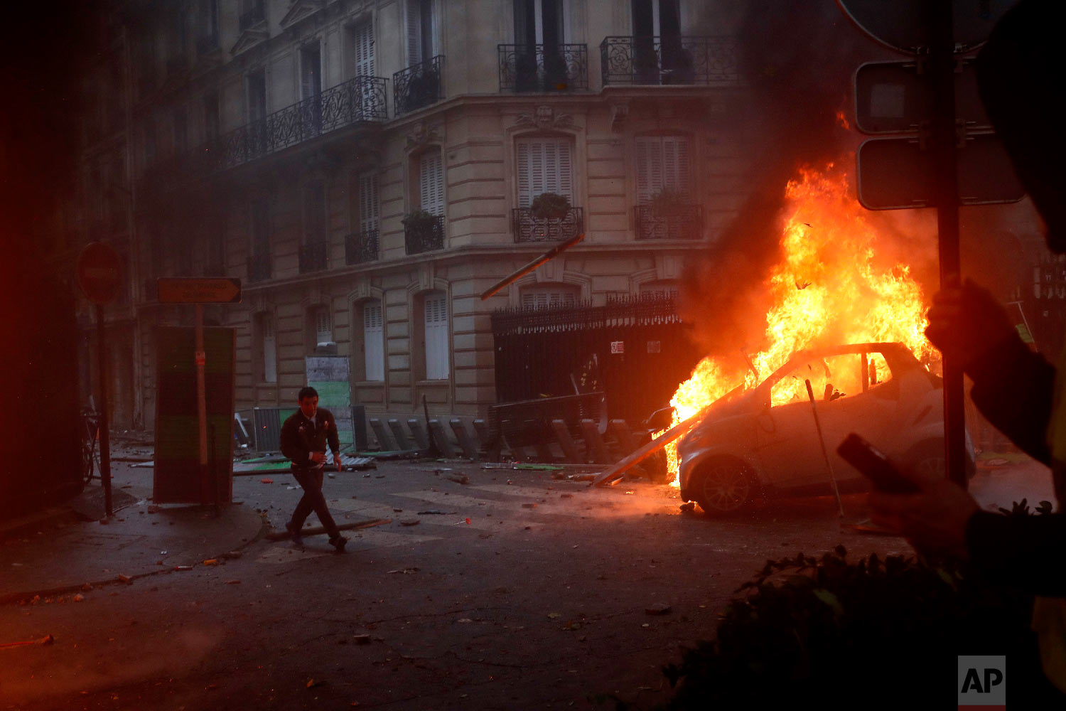  A demonstrator runs pas a burning car during a demonstration in Paris on Dec. 1, 2018. (AP Photo/Thibault Camus) 