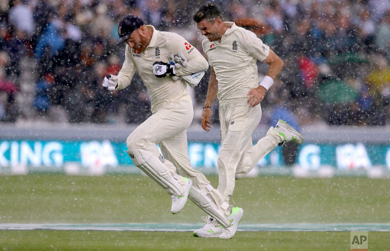  England's Jonny Bairstow and England's James Anderson run off the pitch as sudden heavy rain starts during the second day of the second test match between England and India at Lord's cricket ground in London on Aug. 10, 2018. (AP Photo/Kirsty Wiggle