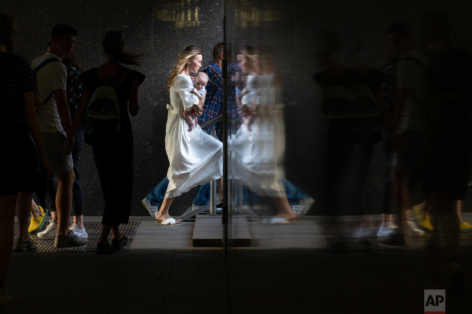  A woman carrying her child is reflected in a wall as she steps up in a subway in Moscow, Russia on Aug. 29, 2018. (AP Photo/Alexander Zemlianichenko) 
