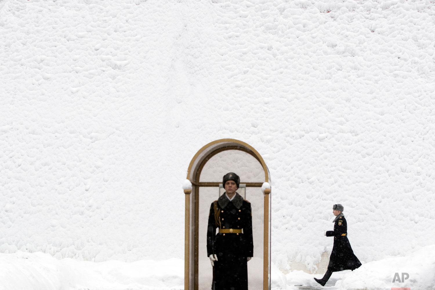  An Honor guard soldier walks along the Kremlin wall, covered by snow, as his fellow soldier stands at the Tomb of Unknown Soldier in Moscow, Russia on Jan. 31, 2018. (AP Photo/Pavel Golovkin) 