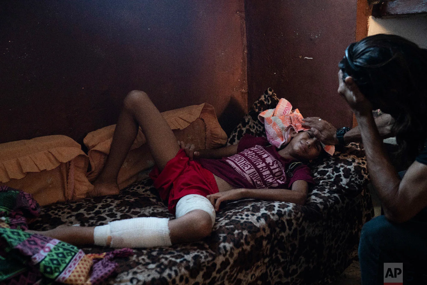 Raed Abu Khader, right, holds a wet cloth on the forehead of his 12-year-old son Mohammed in Gaza City, Sept. 12, 2018. Mohammed was shot in the leg at one of the demonstrations on Gaza strip's border with Israel. (AP Photo/Felipe Dana)