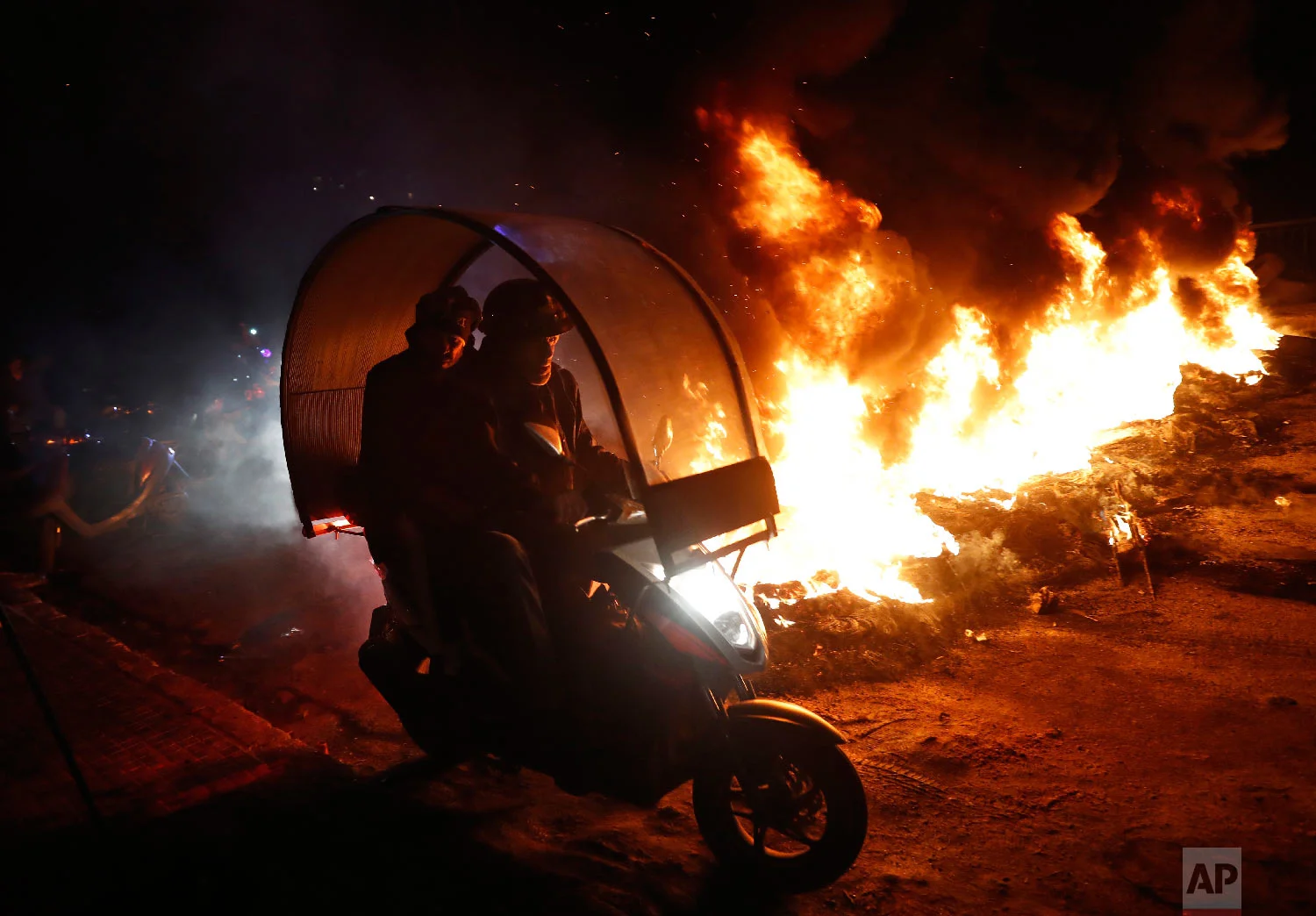 Supporters of Lebanese Parliament Speaker Nabih Berri ride a scooter past a road block, during a protest against Lebanese Foreign Minister Gibran Bassil, in Beirut, Lebanon, Jan. 29, 2018. (AP Photo/Hussein Malla)
