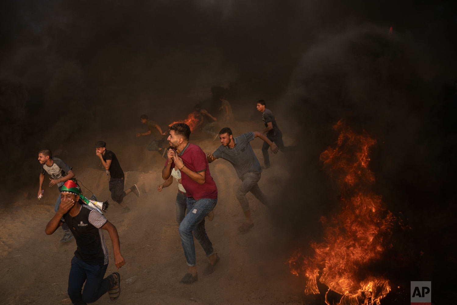 Palestinian protesters run from teargas fired by Israeli troops during a protest at the Gaza Strip's border with Israel, east of Gaza City, Aug. 31, 2018. (AP Photo/Felipe Dana)