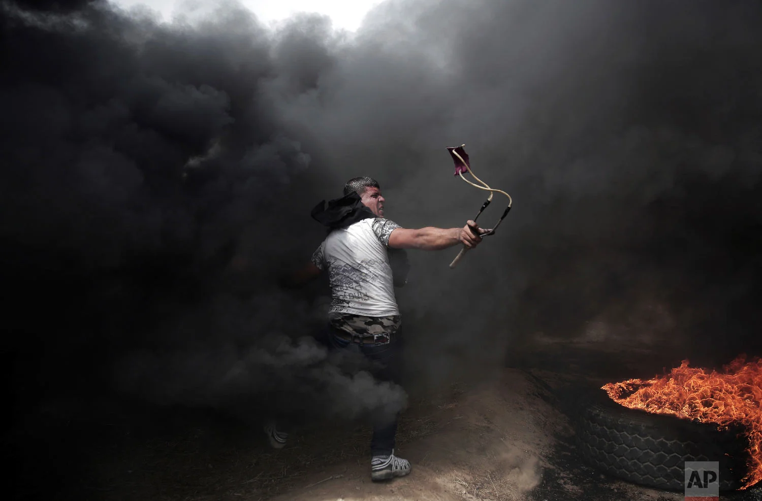 A Palestinian protester hurls stones at Israeli troops during a protest at the Gaza Strip's border with Israel, Friday, April 20, 2018.(AP Photo/ Khalil Hamra)