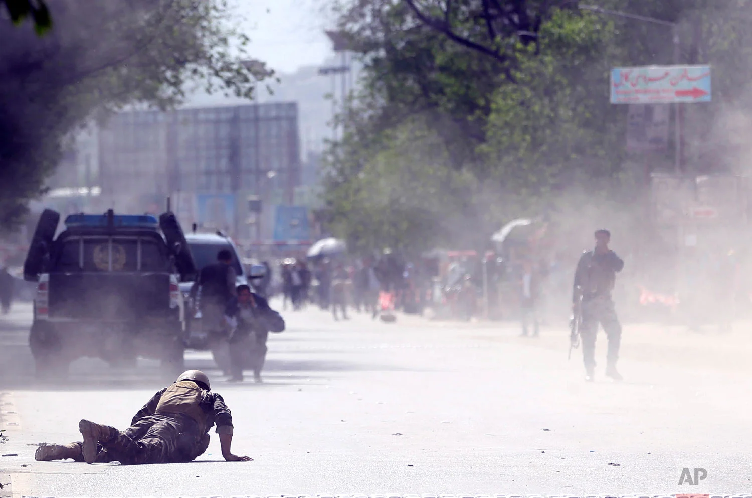 A soldier and a civilian lie low at the site of a suicide attack after the second bombing in Kabul, Afghanistan, April 30, 2018. (AP Photo/Massoud Hossaini)