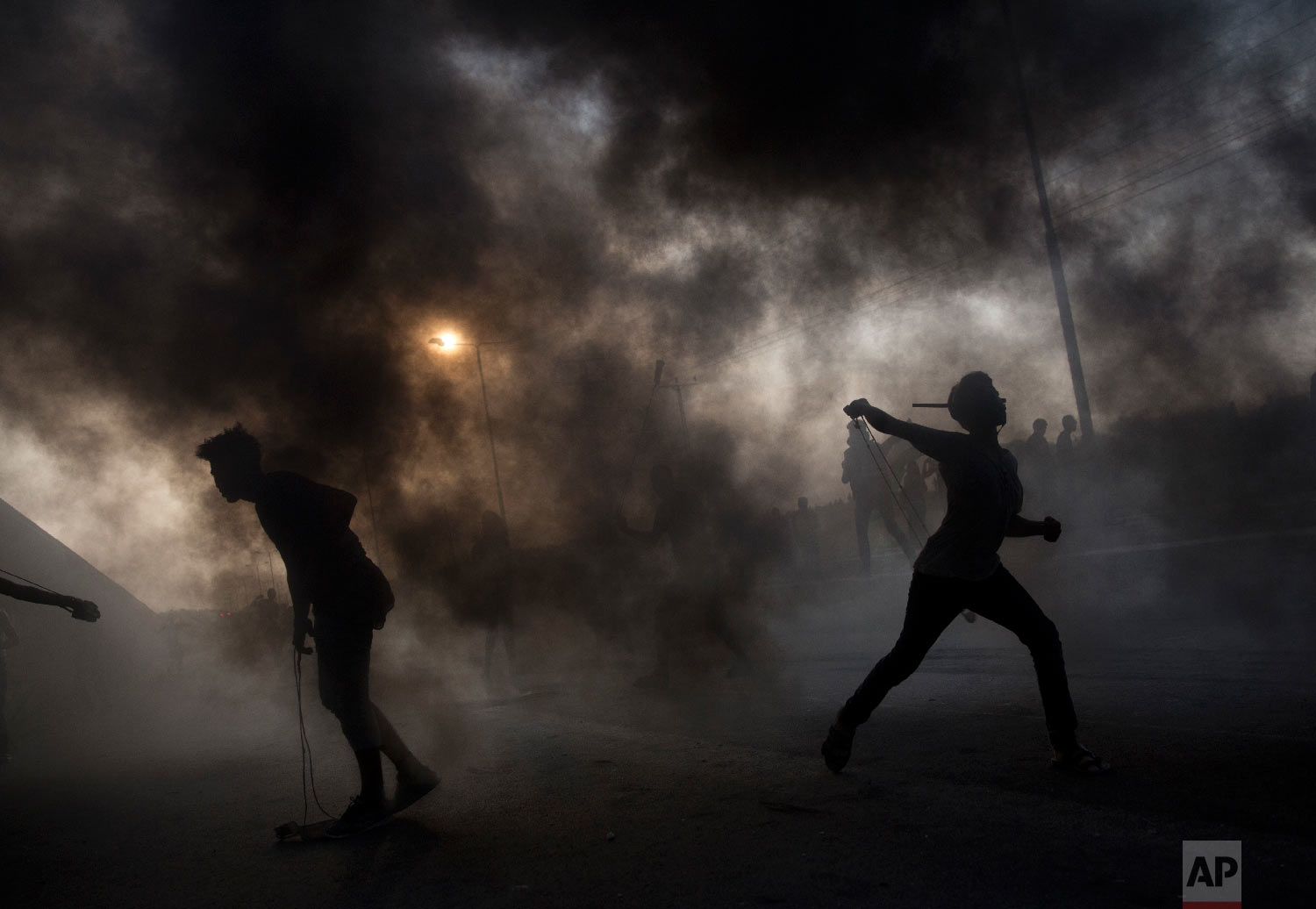 Palestinian protesters hurl stones during a demonstration at the entrance of Erez border crossing between Gaza and Israel, in the northern Gaza Strip, Oct. 3, 2018. (AP Photo/Khalil Hamra)