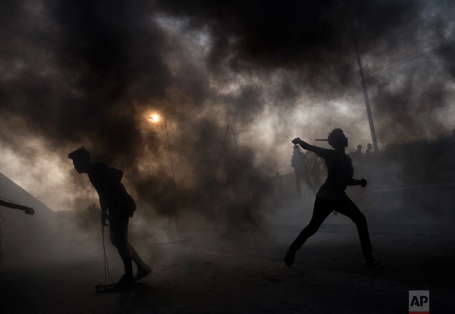 Palestinian protesters hurl stones during a demonstration at the entrance of Erez border crossing between Gaza and Israel, in the northern Gaza Strip, Oct. 3, 2018. (AP Photo/Khalil Hamra)
