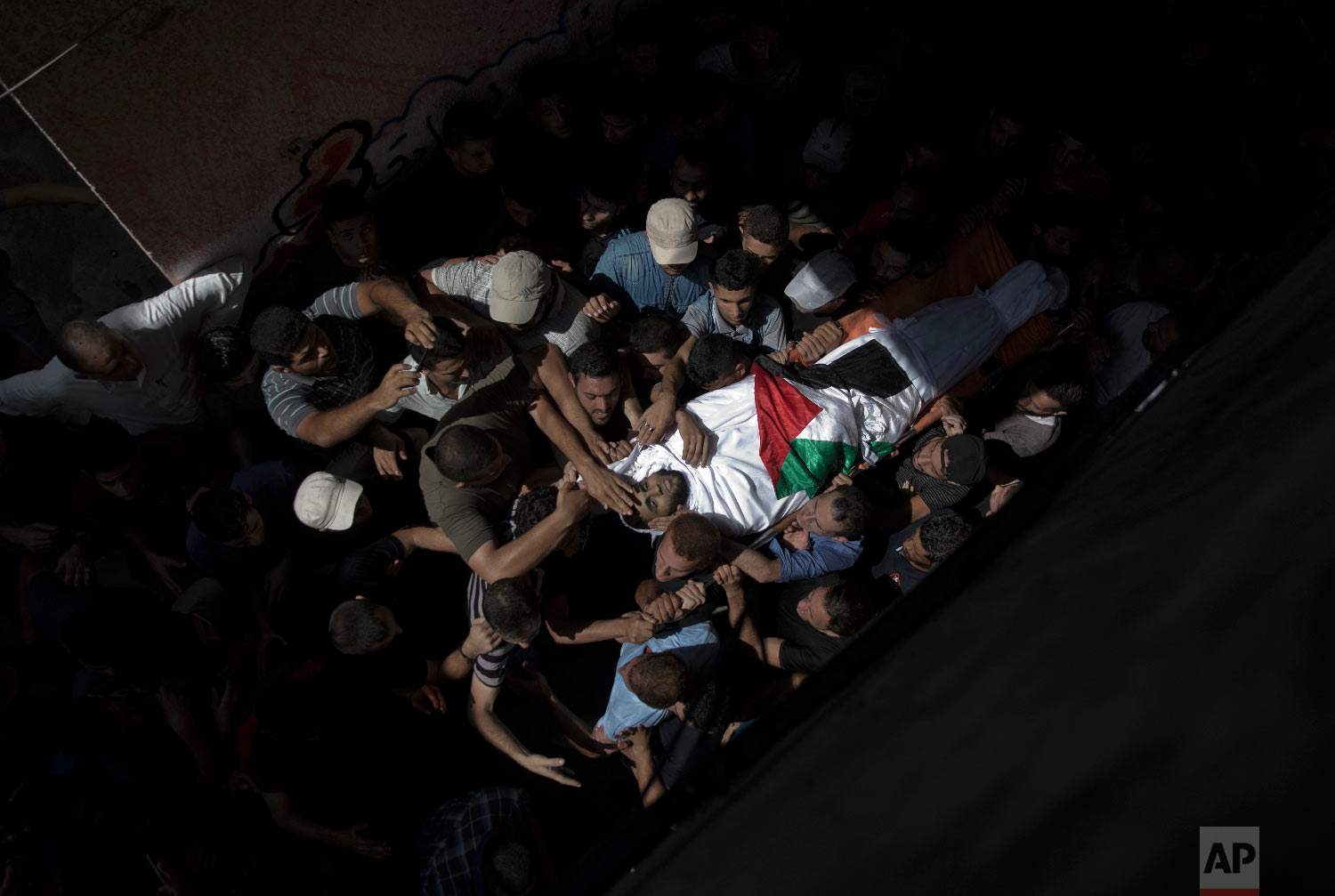 Mourners carry the body of Palestinian Muhammed al-Sadiq, 21, into the family home during his funeral in Gaza City, Sept. 25, 2018. (AP Photo/Khalil Hamra)
