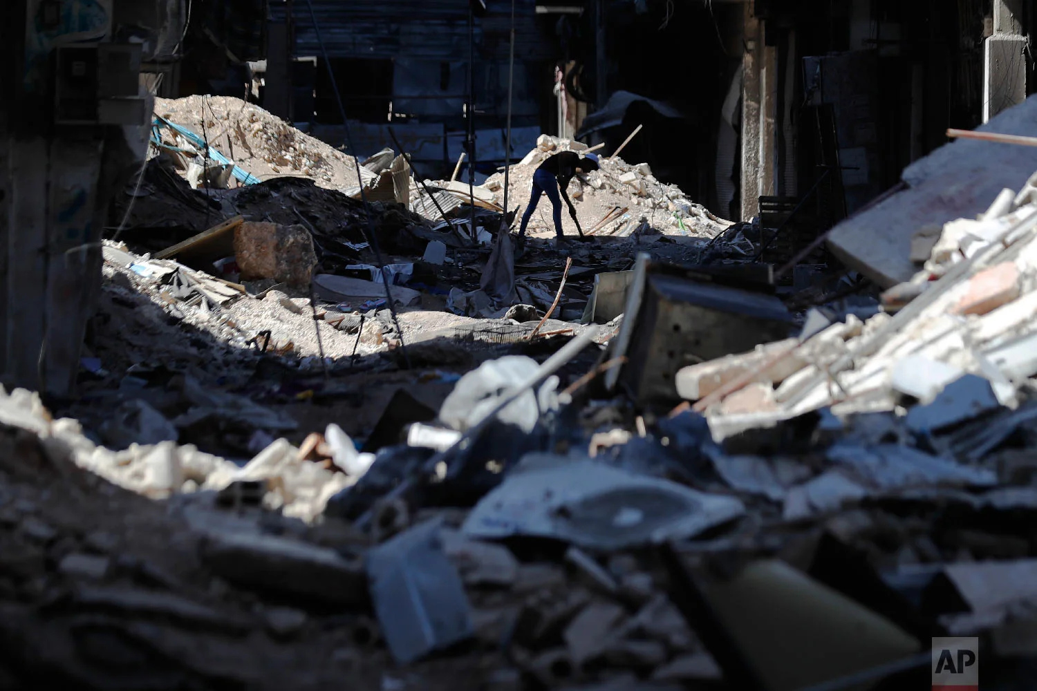 A young man removes rubble in front of his shop in the Palestinian refugee camp of Yarmouk in the Syrian capital Damascus, Syria, July 16, 2018. (AP Photo/Hassan Ammar)