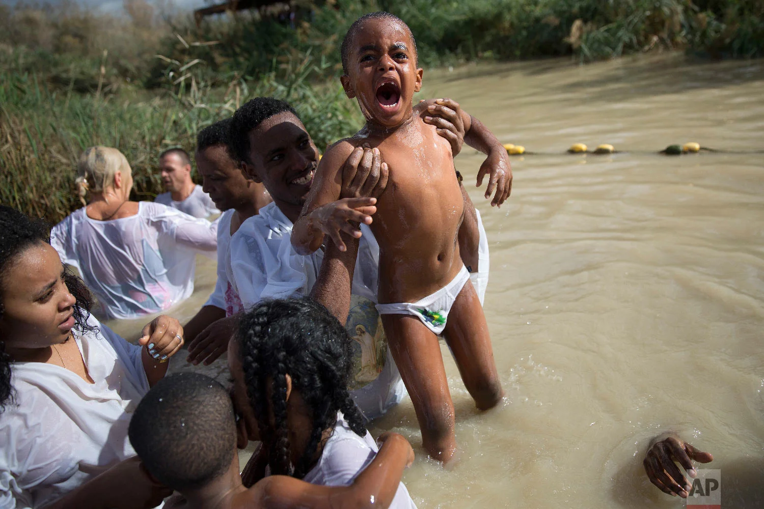 Members of the Eritrean and Ethiopian Christian Orthodox community from Tel Aviv baptized in the waters of the Jordan River during a baptism ceremony as part of the Orthodox Feast of the Epiphany at Qasr el Yahud, the spot where John the Baptist is said to have baptized Jesus, near the West Bank town of Jericho, Jan. 19, 2018. (AP Photo/Oded Balilty)