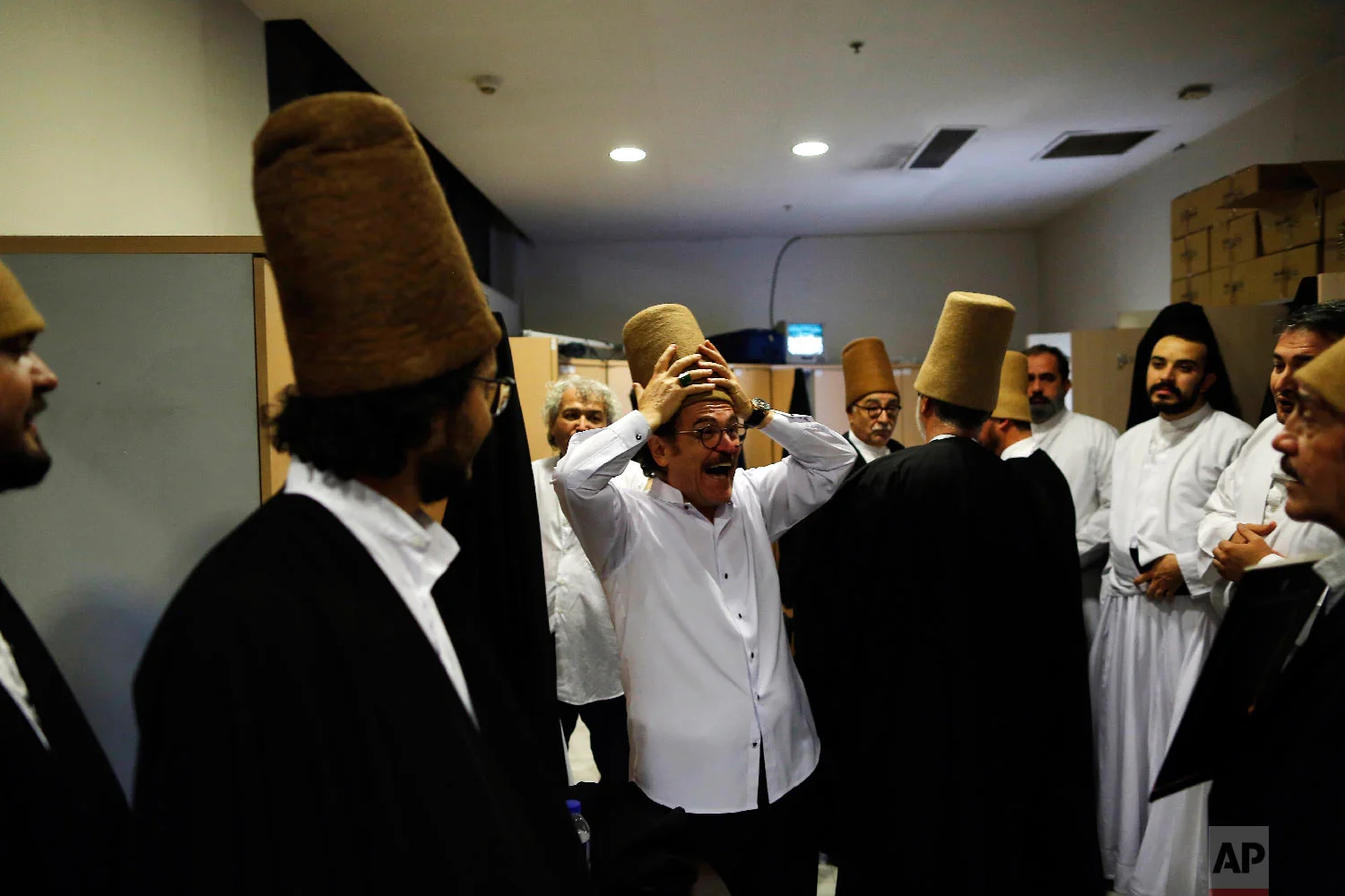 Whirling dervishes of the Mevlevi order enjoy a light moment in the locker room prior to a Sheb-i Arus ceremony in Konya, central Turkey, Sunday, Dec. 16, 2018. (AP Photo/Lefteris Pitarakis)