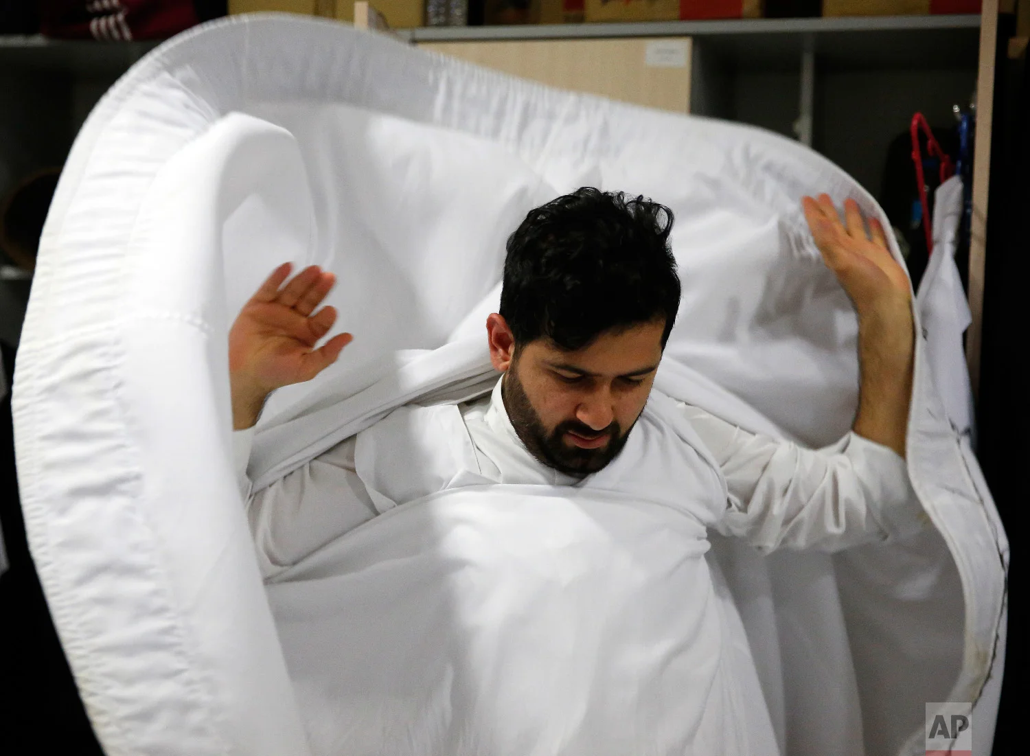 A whirling dervish of the Mevlevi order gets dressed in the locker room prior to a Sheb-i Arus ceremony in Konya, central Turkey, Sunday, Dec. 16, 2018. (AP Photo/Lefteris Pitarakis)