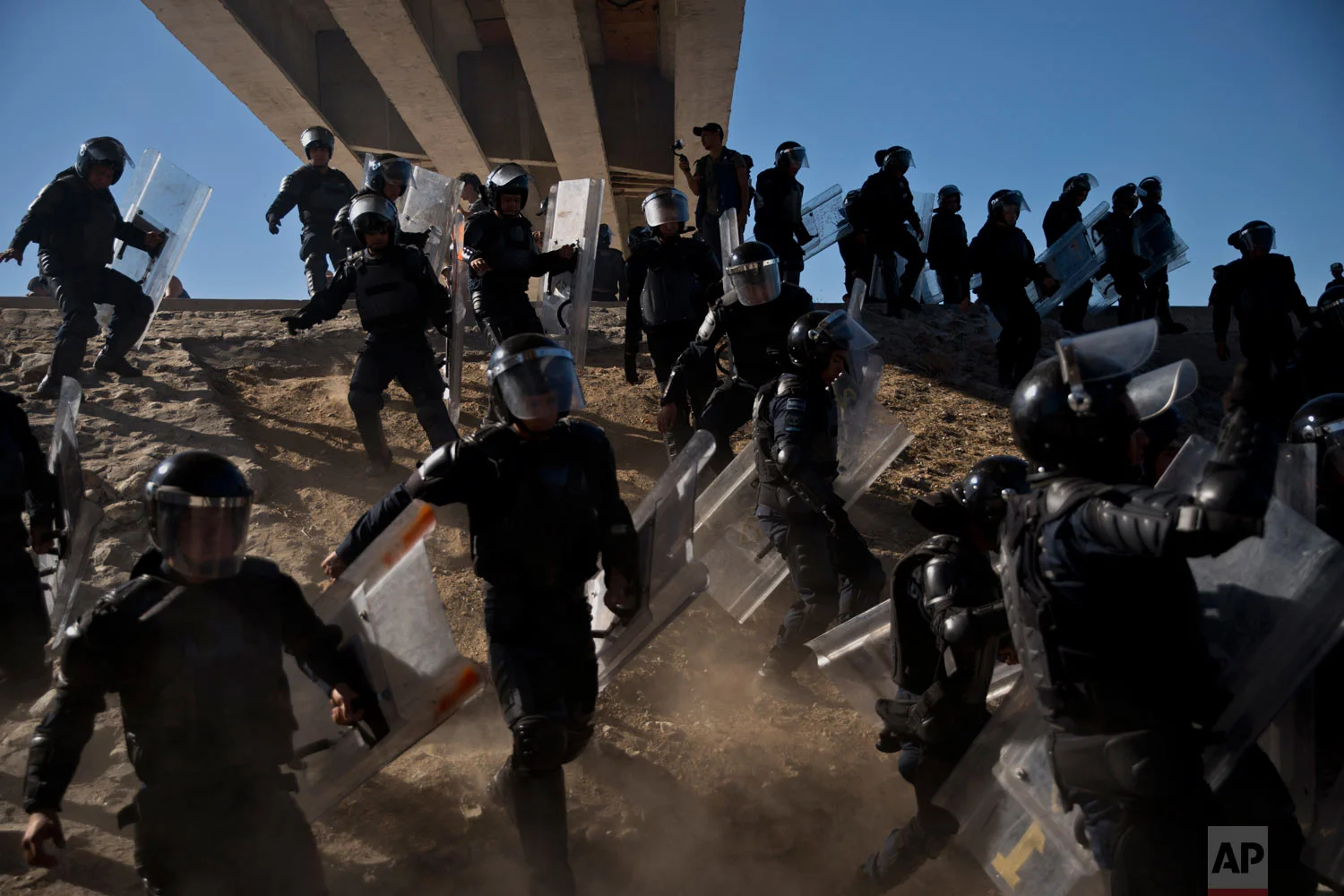 In this Nov. 25, 2018 photo, Mexican police try to keep Central American migrants from getting past the border crossing in Tijuana, Mexico. The mayor of Tijuana declared a humanitarian crisis in his city and said he asked the U.N. for aid to deal with the approximately 5,000 Central American migrants who arrived in caravans. (AP Photo/Ramon Espinosa)