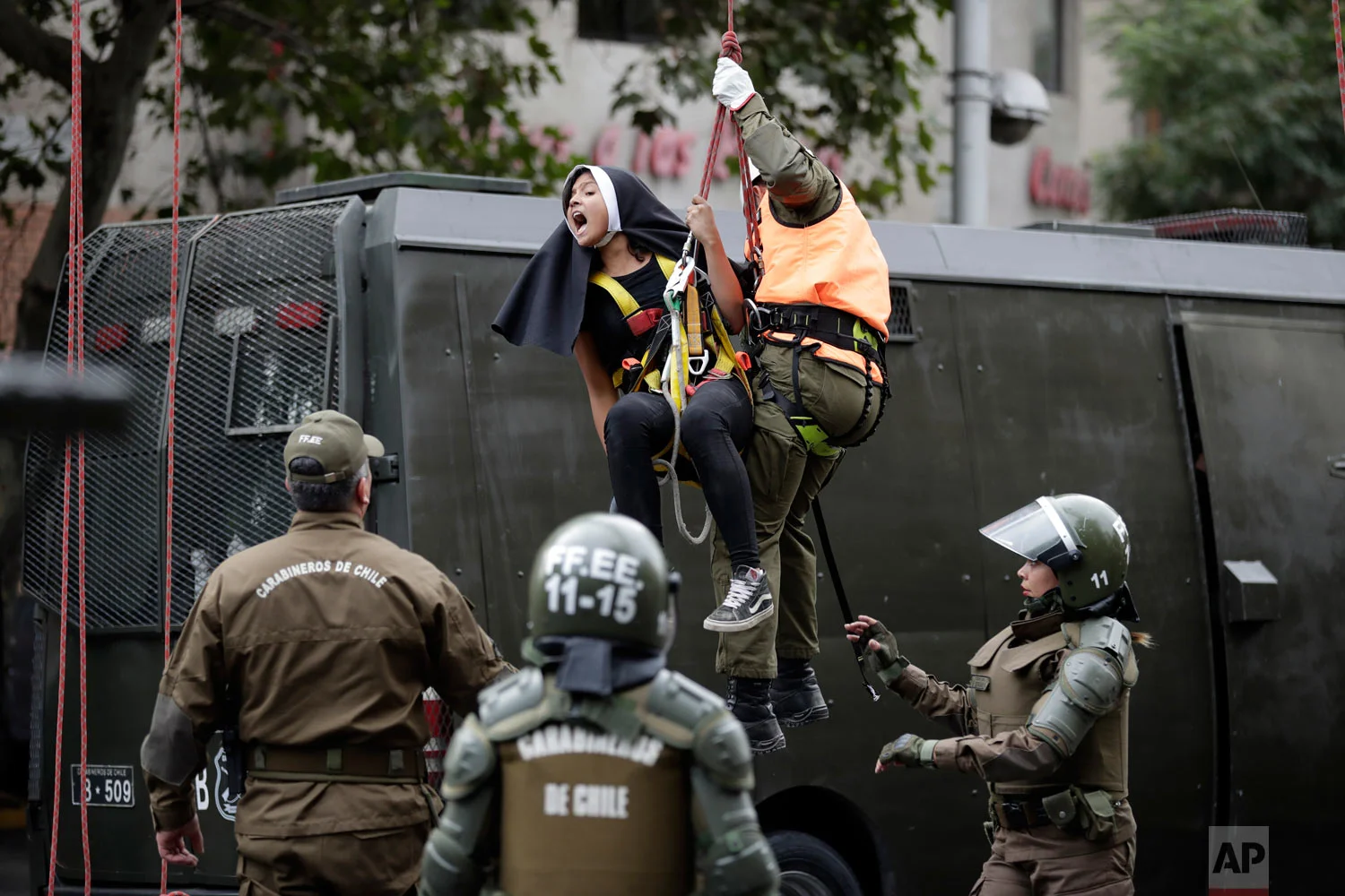 In this Jan. 15, 2018 photo, an activist dressed as a nun shouts as she's lowered and detained by a police after she and others placed a pro-abortion sign above a road near Pope Francis' expected route, before the pontiff's arrival in Santiago, Chile. This year the Argentine pontiff defrocked a Chilean priest who was a central character in the global sex abuse scandal rocking his papacy. (AP Photo/Victor R. Caivano)