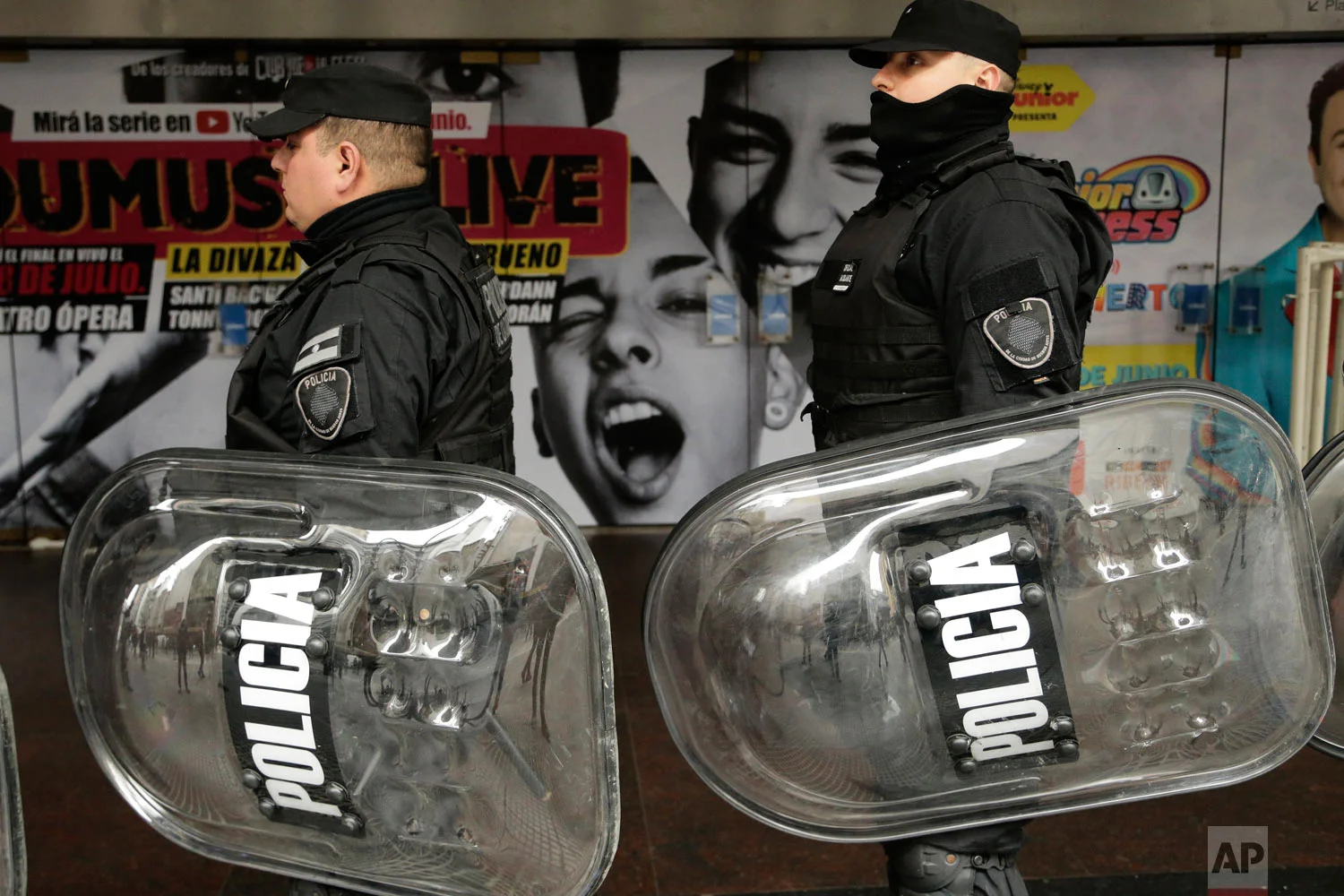 In this July 5, 2018 photo, police carry their shields alongside a march of journalists protesting the layoffs of about 40 percent of the employees from the Telam public news agency in Buenos Aires, Argentina. Argentines have been protesting recent government austerity measures and demanding solutions to the country’s economic crisis. (AP Photo/Jorge Saenz)