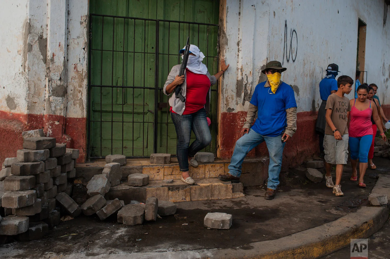 In this July 17, 2018 photo, an armed, pro-government Sandinista militia stands guard at a torn down barricade, which had been set up by anti-government protesters, after police and militias stormed the Monimbo neighborhood of Masaya, Nicaragua. Heavily armed police and militias laid siege to and then retook a symbolically important neighborhood that had recently become a center of resistance to President Daniel Ortega's government. (AP Photo/Cristobal Venegas)