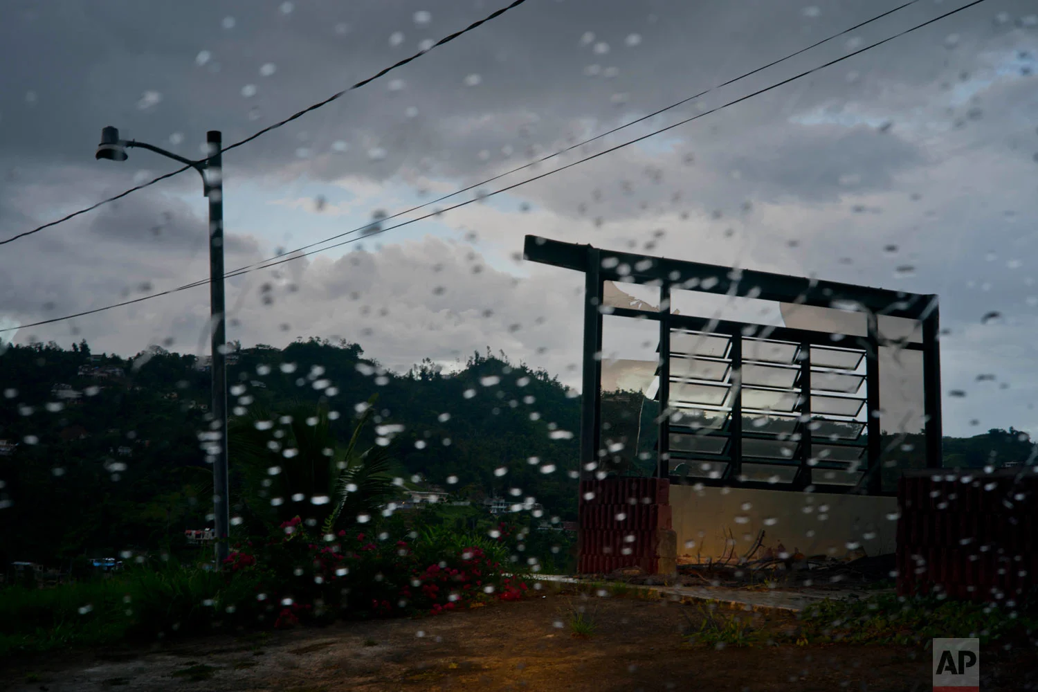 In this Sept. 11, 2018 photo, a lone wall from a home destroyed one year prior by Hurricane Maria stands in the mountain town of Naranjito, Puerto Rico. Maria destroyed over 200,000 homes on the island. (AP Photo/Ramon Espinosa)