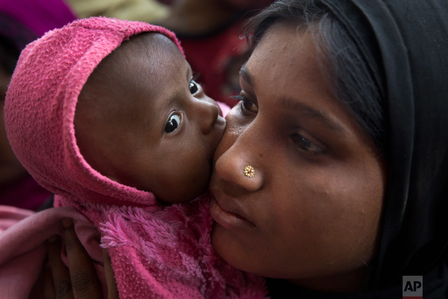 A newly arrived Rohingya refugee child licks the cheek of her mother Azida Khatoon, 20, as they wait in a food distribution line in the Kutupalong refugee camp near Cox's Bazar, Bangladesh on Jan. 27, 2018. (AP Photo/Manish Swarup)