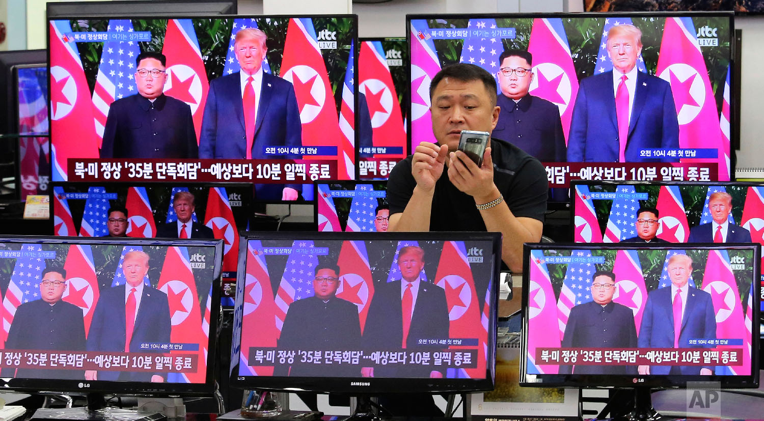  TV screens show U.S. President Donald Trump, right, meeting with North Korean leader Kim Jong Un in Singapore, during a news program at Yongsan Electronic store in Seoul, South Korea on June 12, 2018. (AP Photo/Ahn Young-joon) 