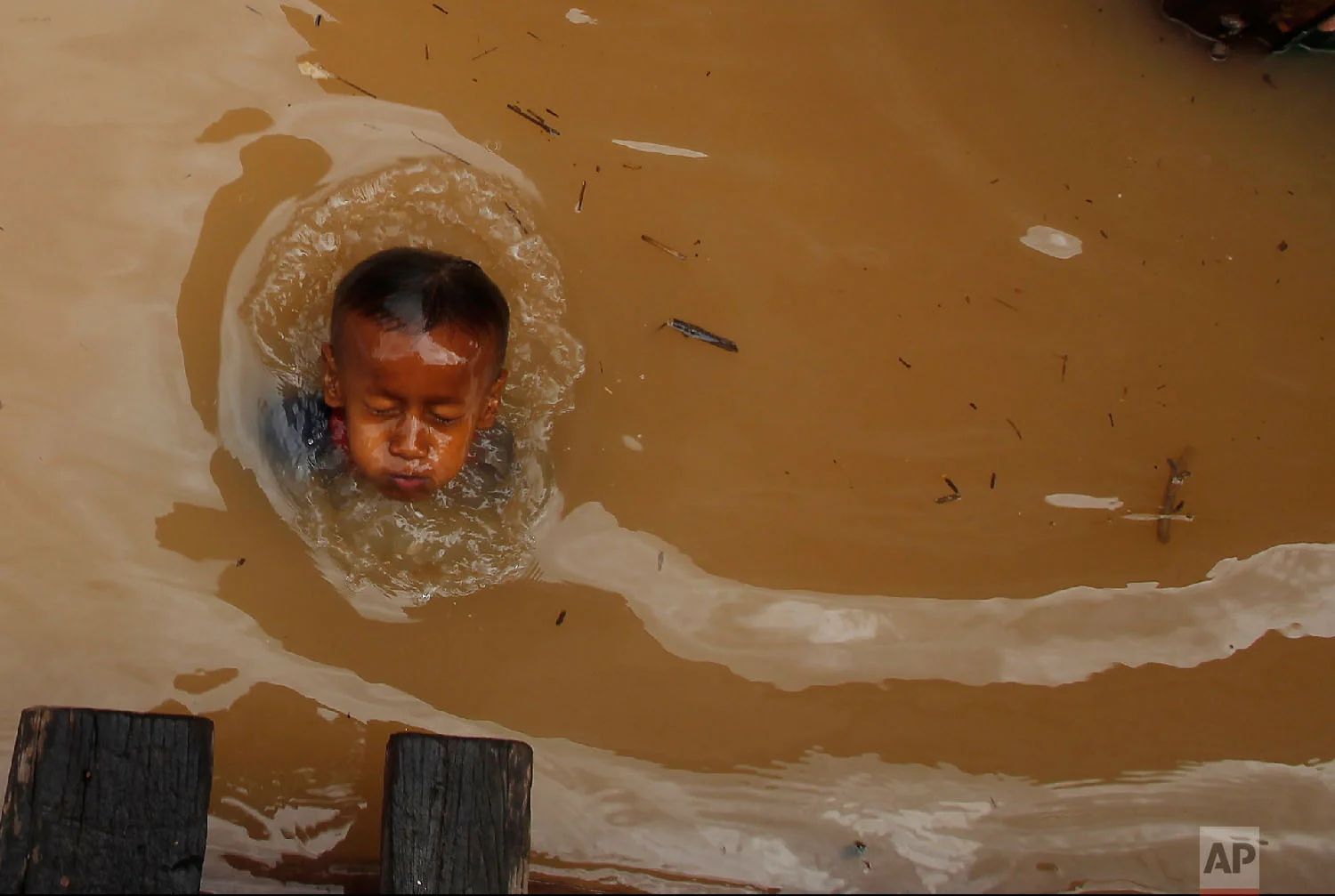 A boy swims during a flood season in the floating village on the Mekong river bank on the outskirts of Phnom Penh, Cambodia, on Aug. 11, 2018. (AP Photo/Heng Sinith)