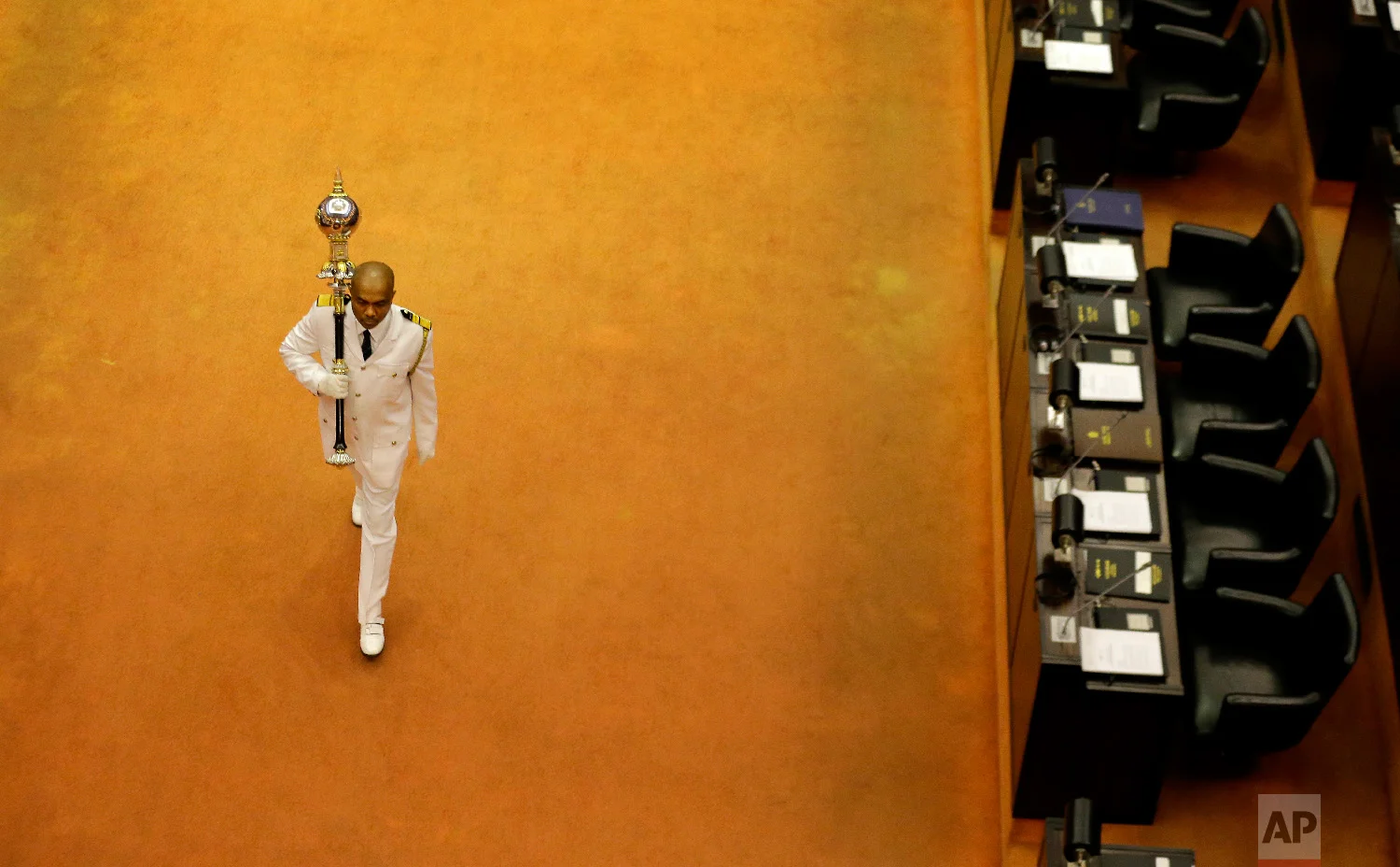 Sri Lanka's sergeant at arms Narendra Fernando walks carrying the mace in the well of the house past empty seats of President Maithripala Sirisena and disputed Prime Minister Mahinda Rajapaksa at the beginning of the parliamentary session in Colombo, Sri Lanka, on Dec. 5, 2018. (AP Photo/Eranga Jayawardena)