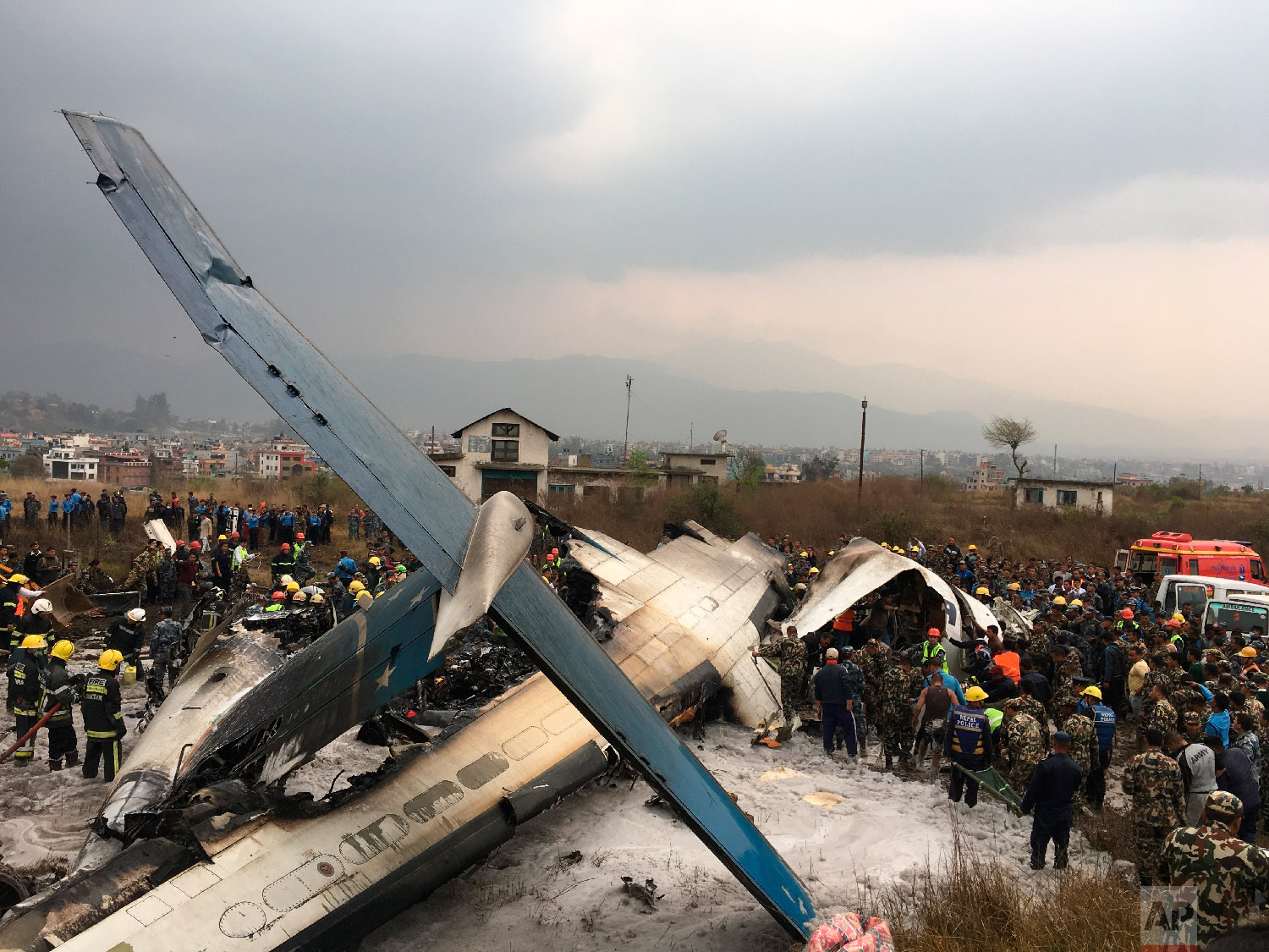  Nepalese rescuers stand near a passenger plane from Bangladesh that crashed at the airport in Kathmandu, Nepal, on March 12, 2018. (AP Photo/Niranjan Shreshta) 