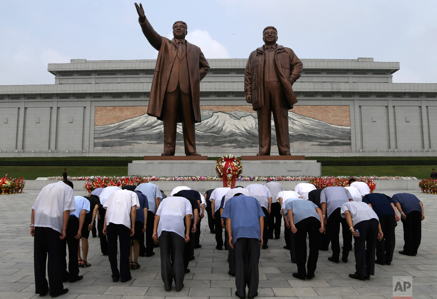  North Korean men bow at the giant bronze statues of late North Korean leaders Kim Il Sung and his son Kim Jong Il during the commemoration of the 65th anniversary of the ceasefire armistice that ended the fighting in the Korean War, which the countr