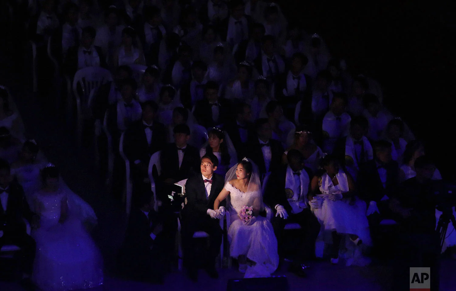 A couple watches a screen during a mass wedding ceremony at the Cheong Shim Peace World Center in Gapyeong, South Korea Monday, Aug. 27, 2018. South Korean and foreign couples exchanged or reaffirmed marriage vows in the Unification Church's mass wedding arranged by Hak Ja Han Moon, wife of the late Rev. Sun Myung Moon, the controversial founder of the Unification Church. (AP Photo/Ahn Young-joon)