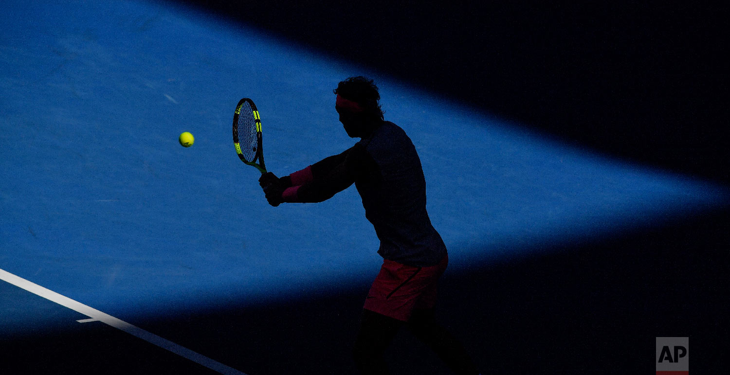Spain's Rafael Nadal is silhouetted as he makes a backhand to Argentina's Leonardo Mayer during their second round match at the Australian Open tennis championships in Melbourne, Australia, Wednesday, Jan. 17, 2018. (AP Photo/Andy Brownbill)