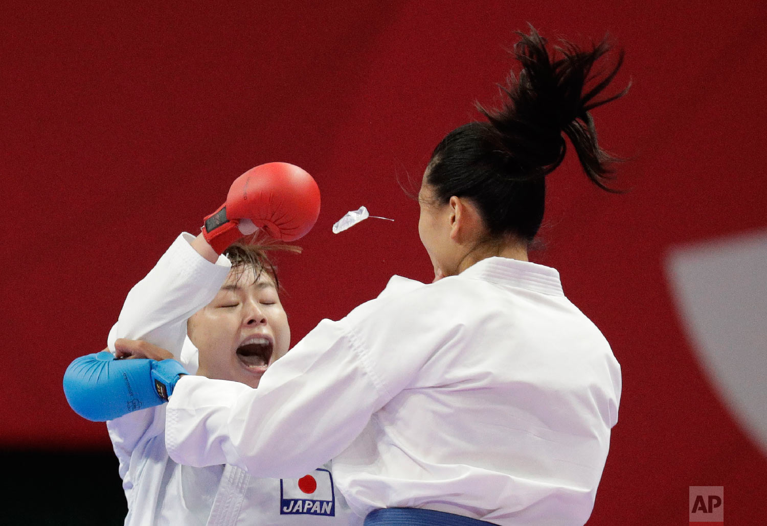  The mouthpiece of China's Mengmeng Gao, right, flies out during her fight with Japan's Ayumi Uekusa during their women's 68kg kumite karate at the 18th Asian Games in Jakarta, Indonesia, Saturday, Aug. 25, 2018. Uekusa won the gold. (AP Photo/Aaron 