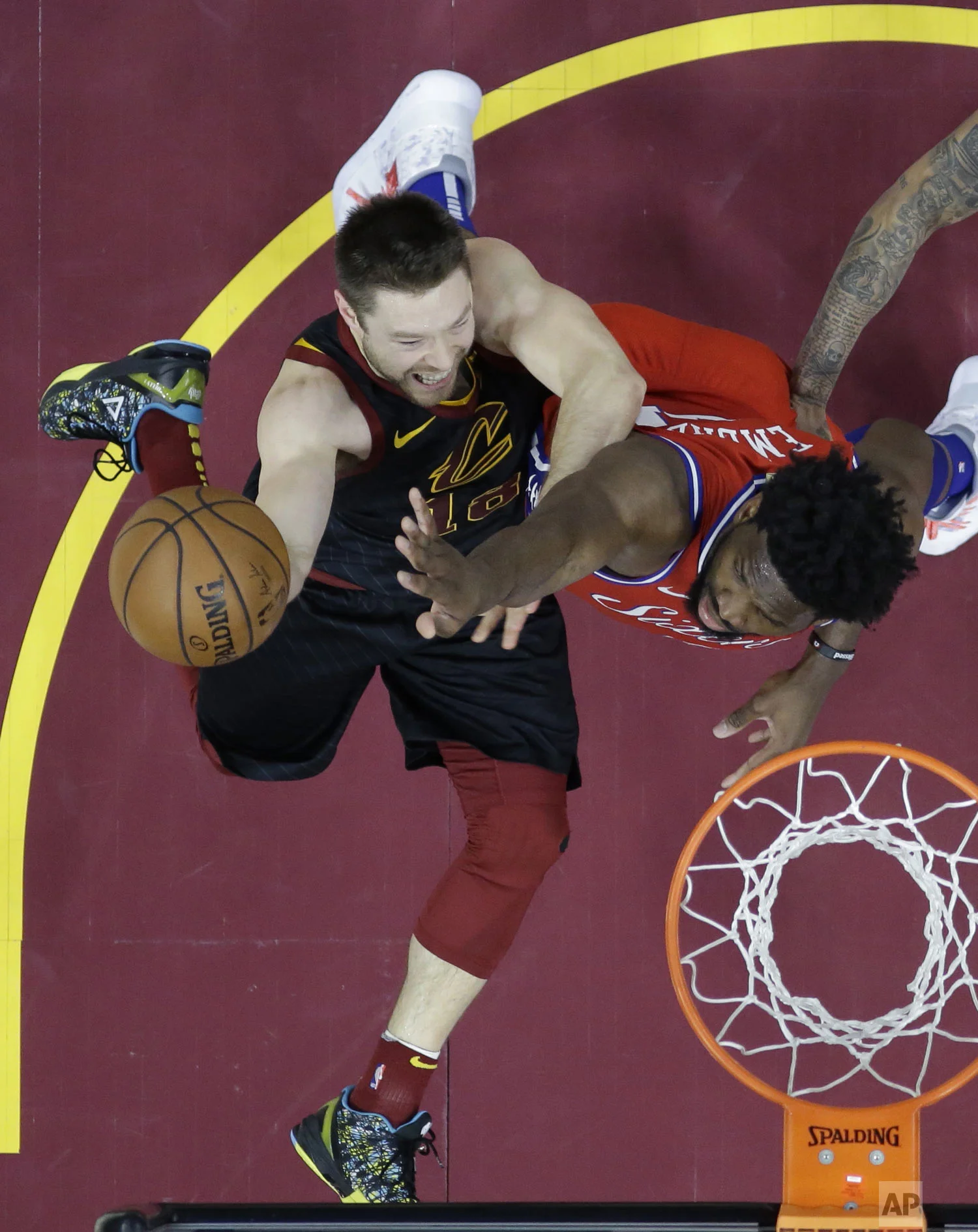 Cleveland Cavaliers' Matthew Dellavedova (18) shoots against Philadelphia 76ers' Joel Embiid (21), from Cameroon, during the first half of an NBA basketball game Sunday, Dec. 16, 2018, in Cleveland. (AP Photo/Ron Schwane)
