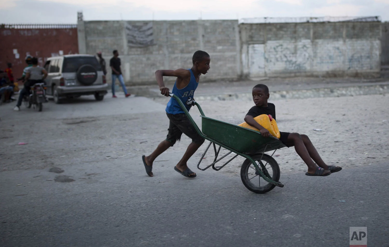Brothers head to a public fountain with a wheelbarrow to fill their container with water to use at home to drink, cook and bathe, in the Cite Soleil slum of Port-au-Prince, Haiti, Tuesday, Dec. 18, 2018. (AP Photo/Dieu Nalio Chery)