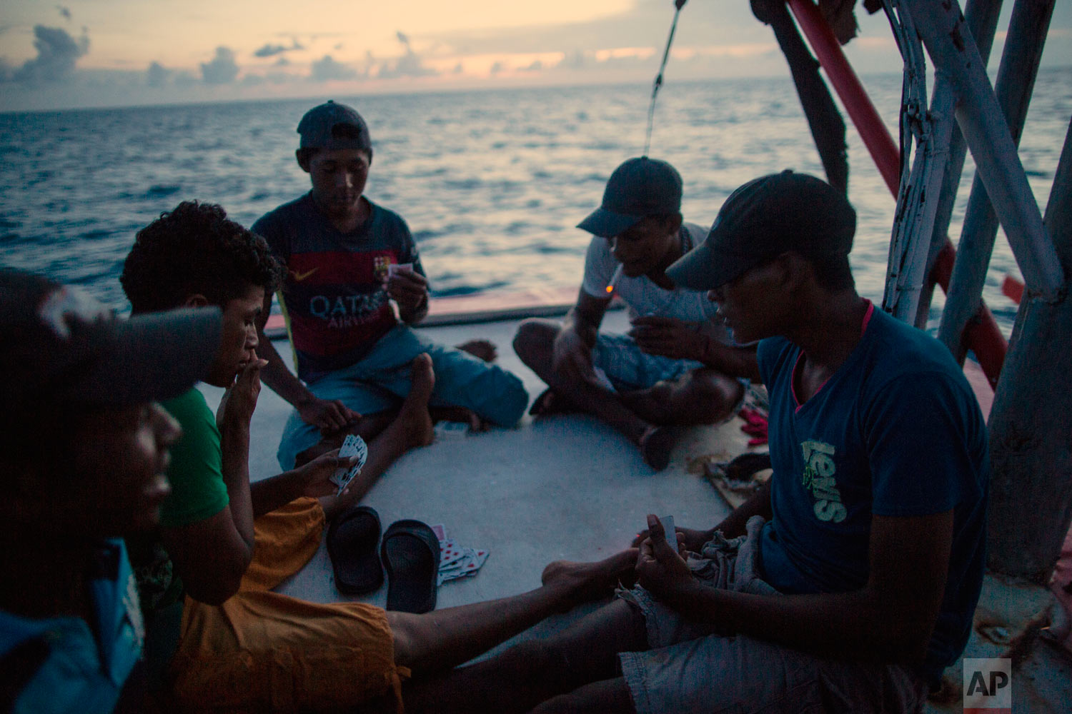  In this Sept. 10, 2018 photo, Miskito divers play a game of cards on a ship’s stern as they are transported home after a two week fishing trip, near the Savannah Cay, Honduras. (AP Photo/Rodrigo Abd) 