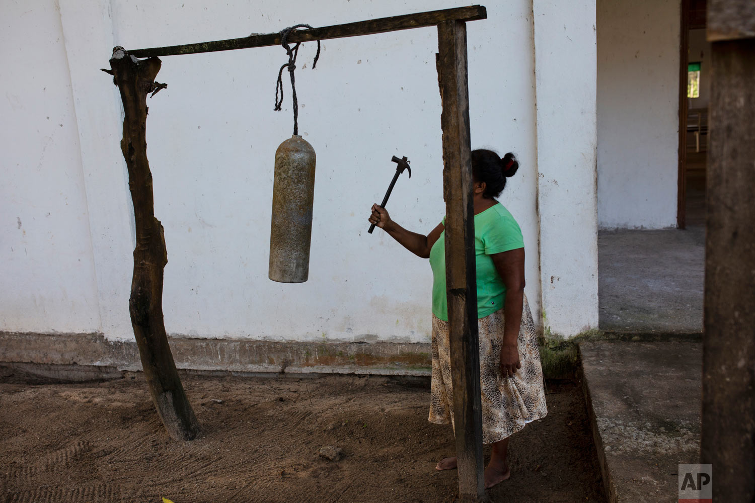  In this Feb. 11, 2018 photo, Elvira Mendoza Espinosa, hits a diving tank with a hammer announcing the start of the morning Mass, outside the Moravian church in Kaukira, Honduras. (AP Photo/Rodrigo Abd) 