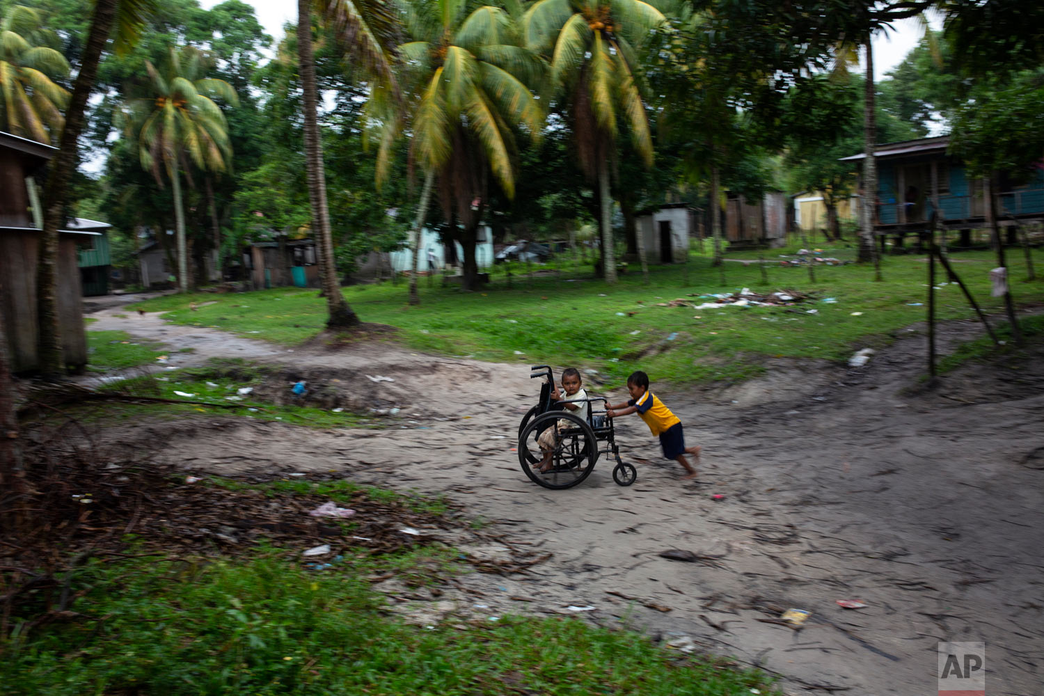  In this Feb. 6, 2018 photo, Charles Melendez, 5, and his 4-year-old brother Jefferson, play with their father’s wheelchair while he rests, in Puerto Lempira, Honduras. (AP Photo/Rodrigo Abd) 