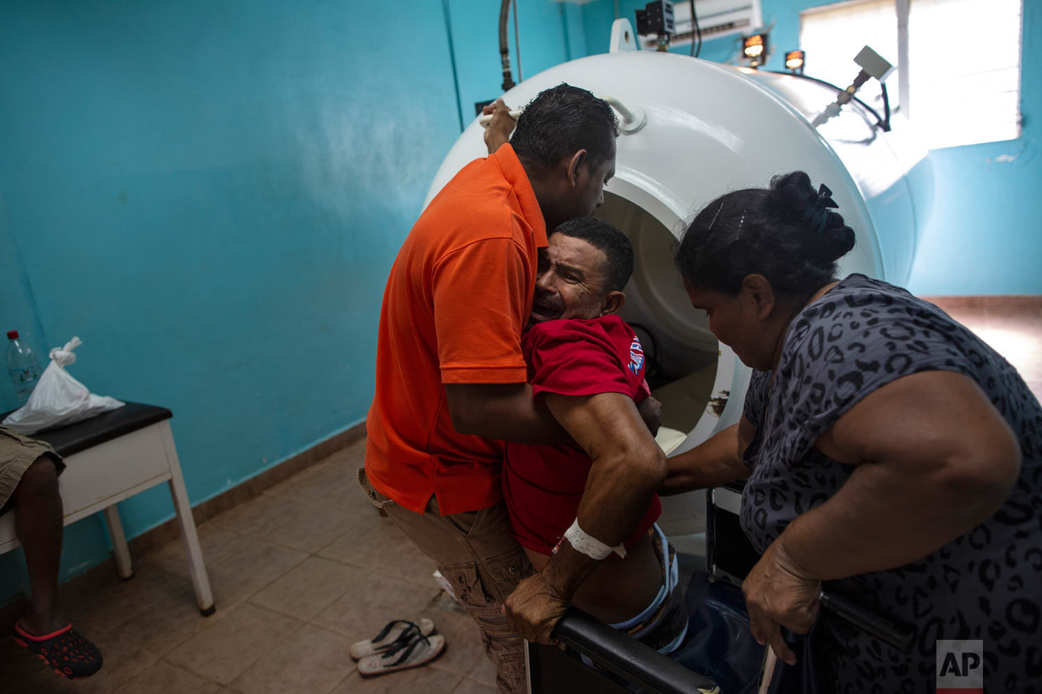  In this Feb. 9, 2018 photo, paralyzed by decompression sickness, lobster diver Misael Banegas Diaz, 49, is lifted by physical therapist Cedrak Waldan Mendoza into a hyperbaric chamber at the hospital in Puerto Lempira, Honduras. (AP Photo/Rodrigo Ab