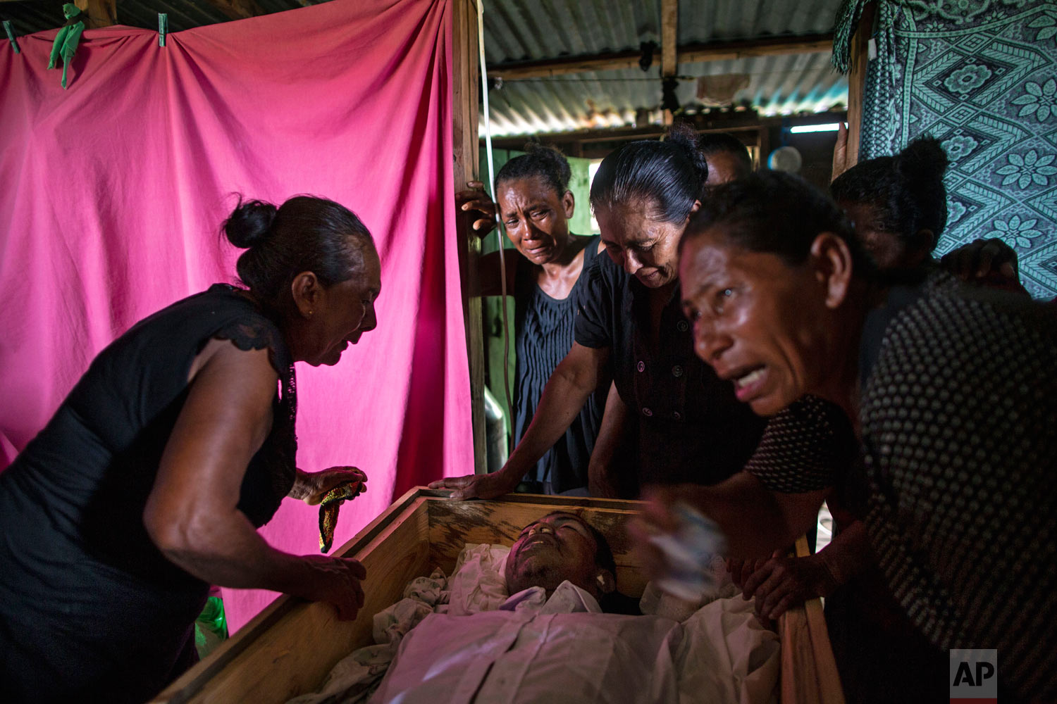  In this Sept. 2, 2018 photo, Sonia Wills, left, accompanied by relatives, mourns over the coffin that contain the remains of her son, Miskito diver Oscar Salomon Charly, 31, during a wake in her home, in Cabo Gracias a Dios, Nicaragua. (AP Photo/Rod